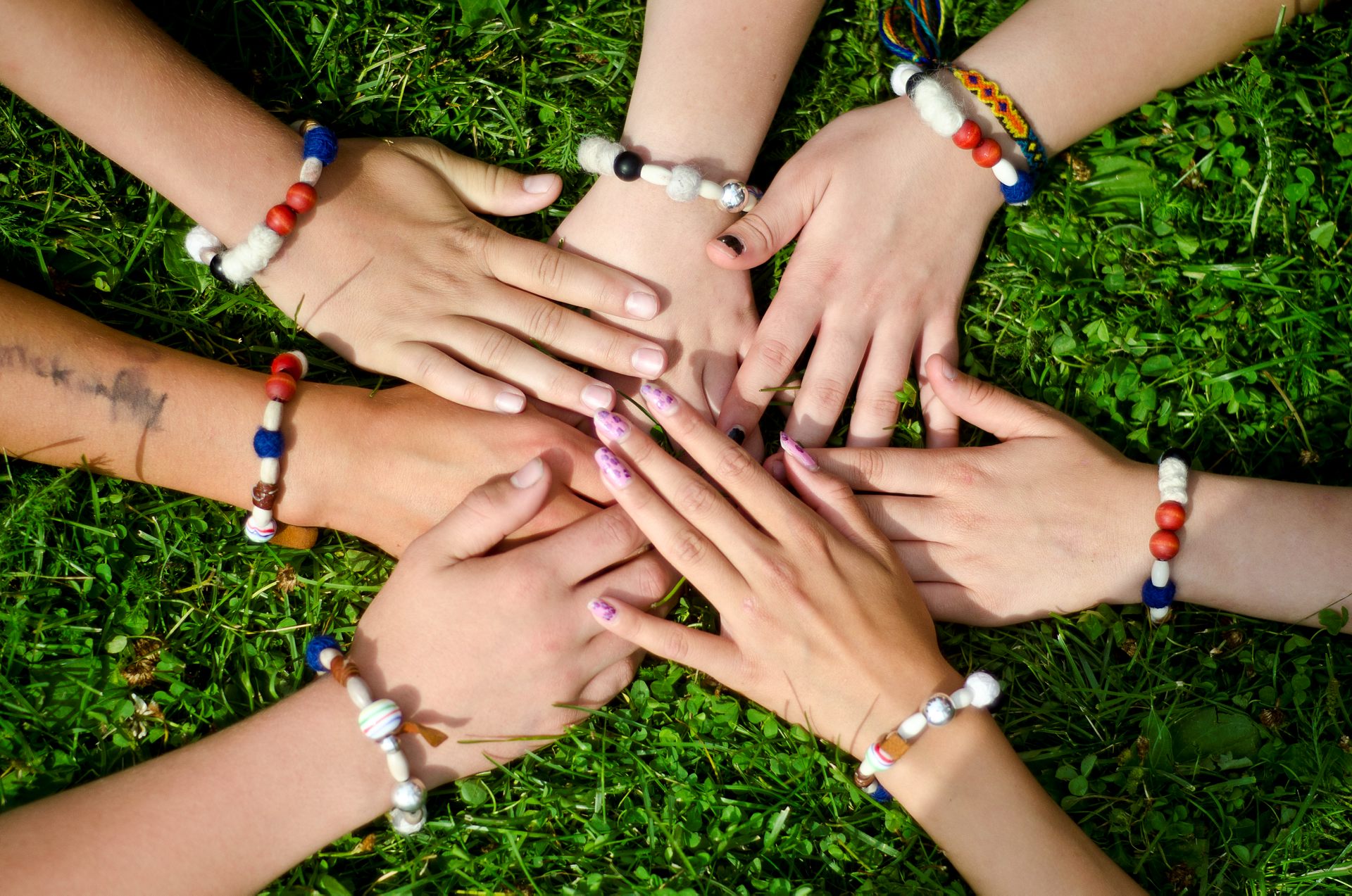 Sju händer ligger i en cirkel. Runt varje handled finns en frälsarkrans.