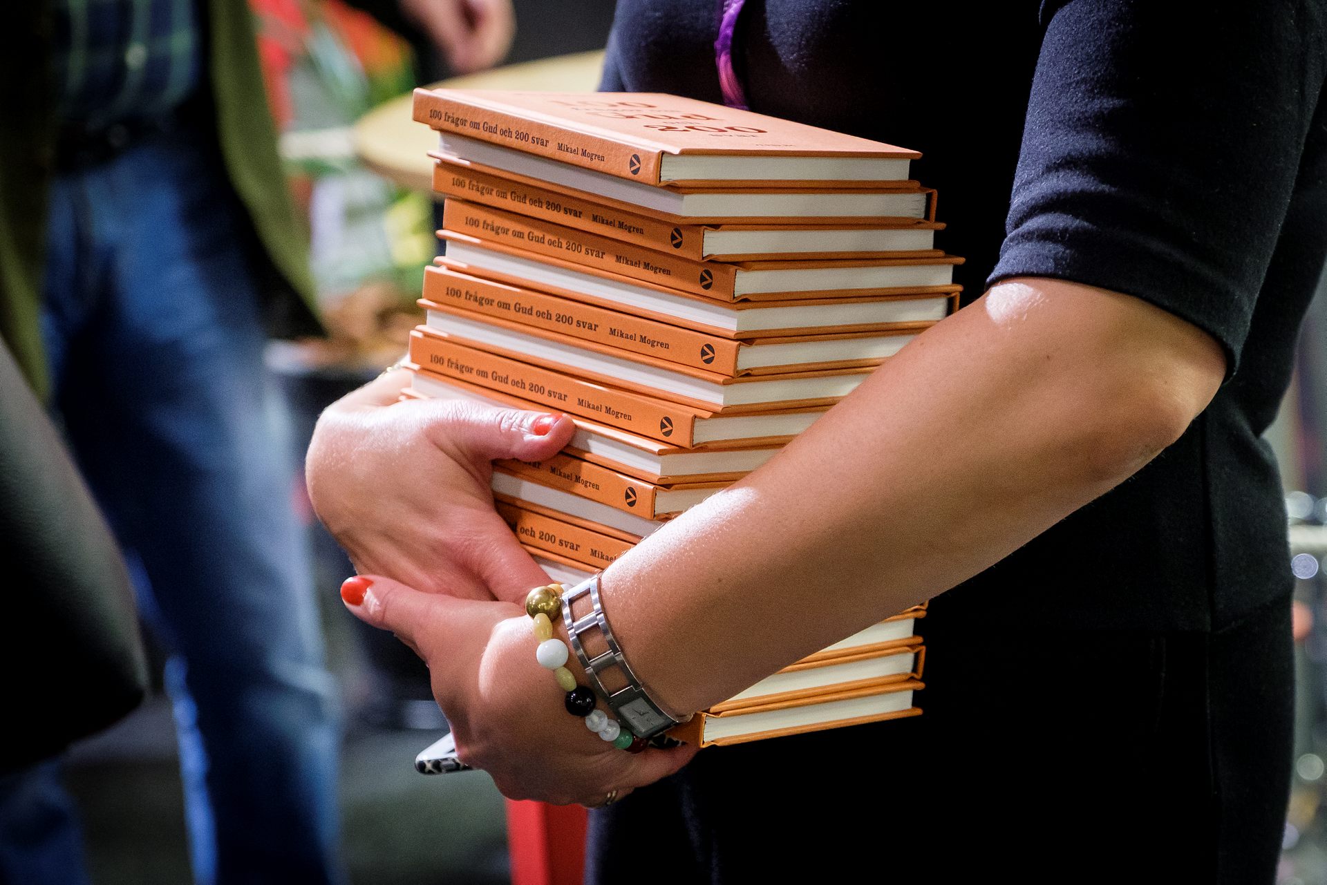 Kvinna bär många orangea böcker.