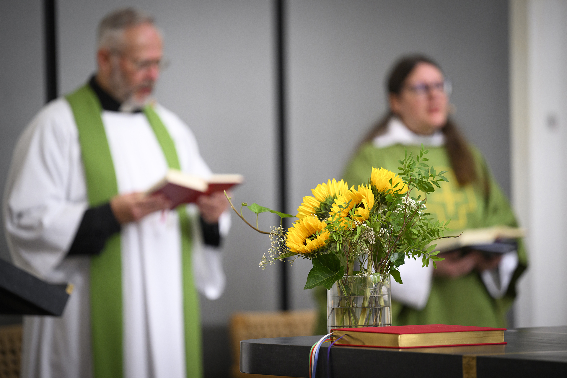 Två präster, en man och kvinna i prästkläder håller gudstjänst