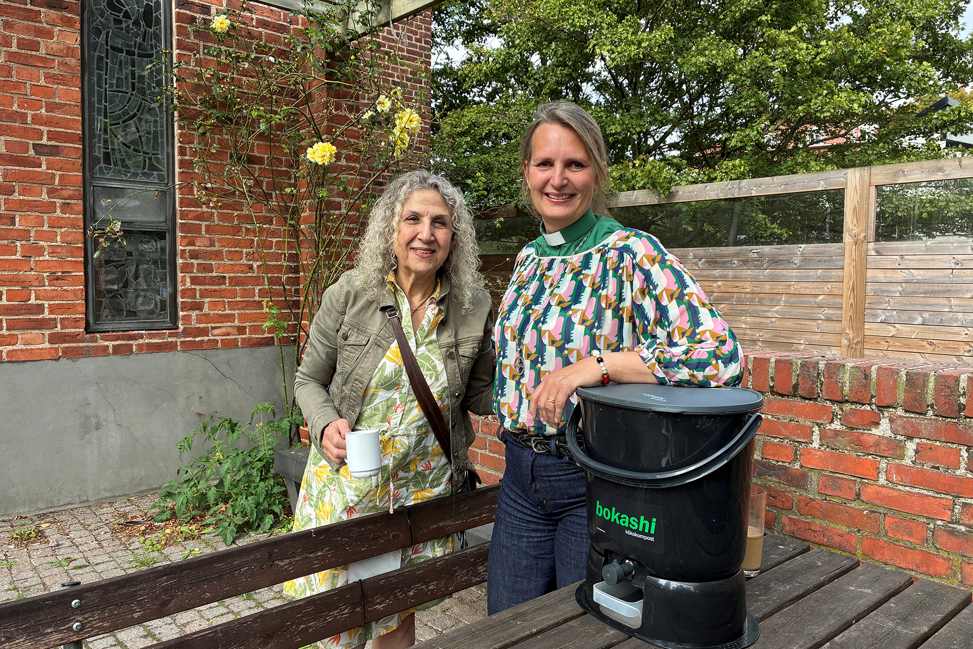 Två kvinnor utomhus med en bokashi-hink