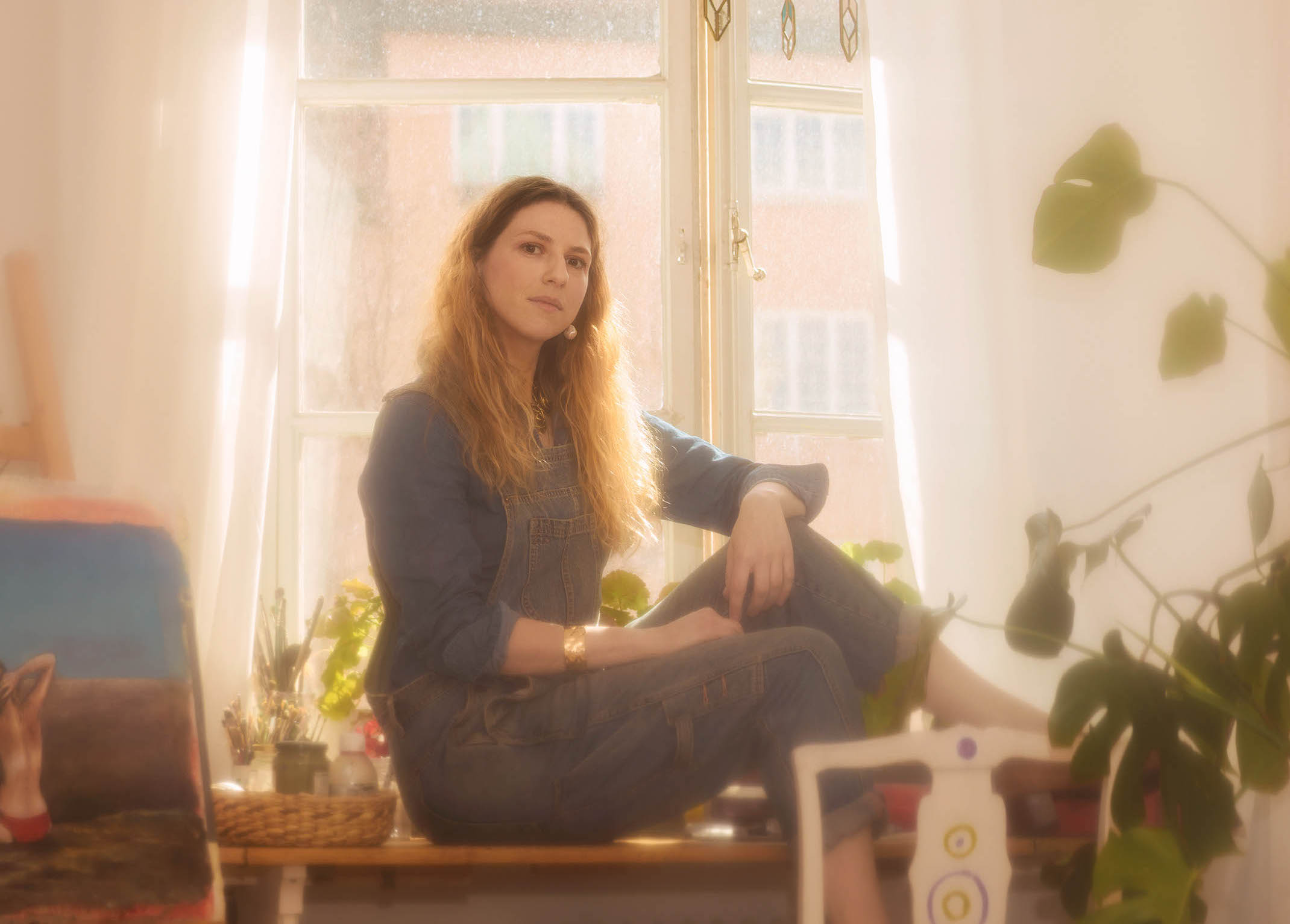 Kvinna med långt hår sitter i fönsterkarm