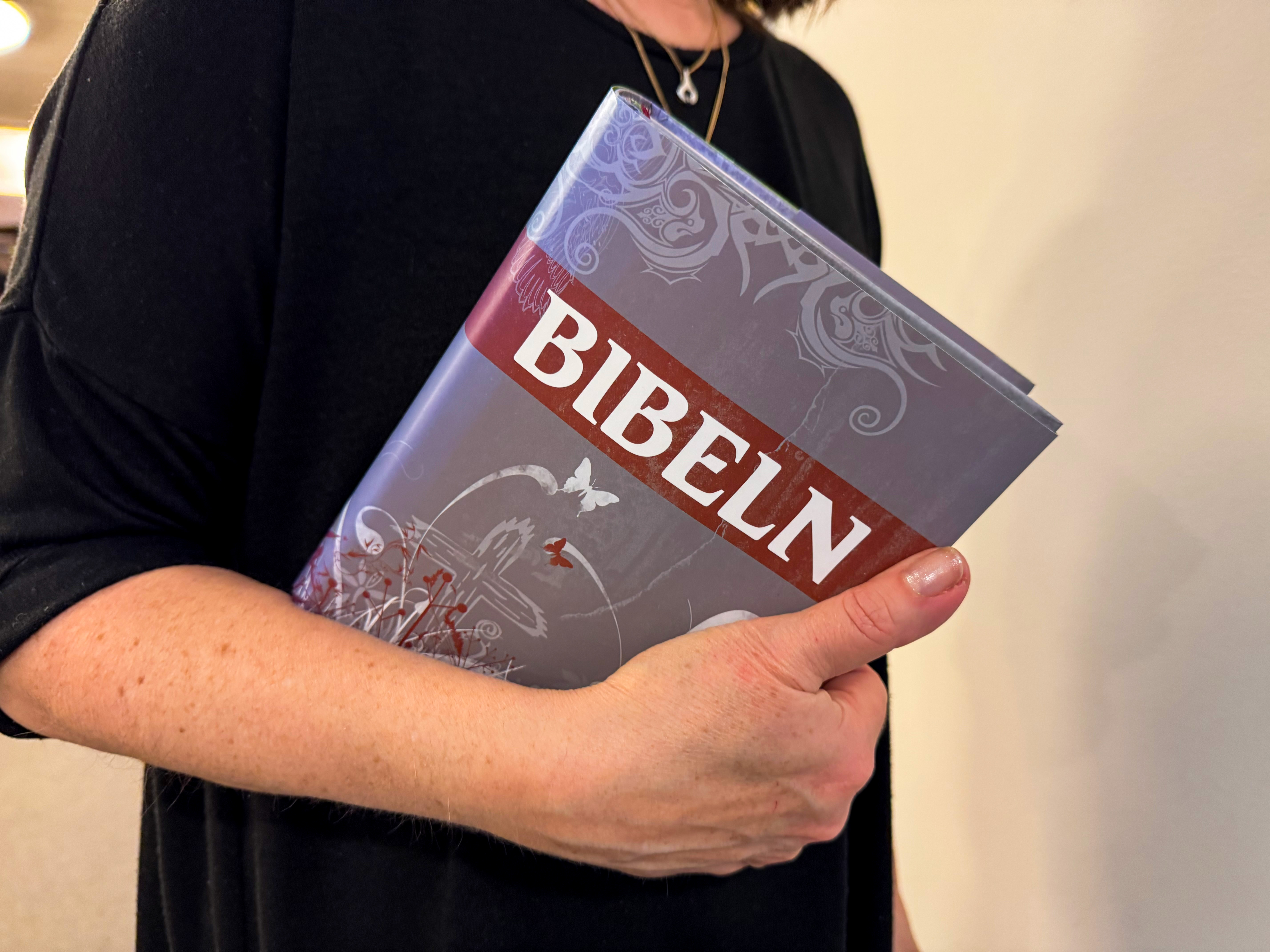 Hand om håller i bibel.