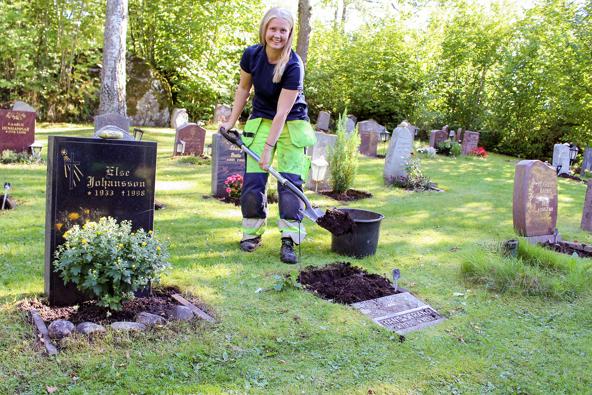 Kvinna som fyller på jord vid en gravsten