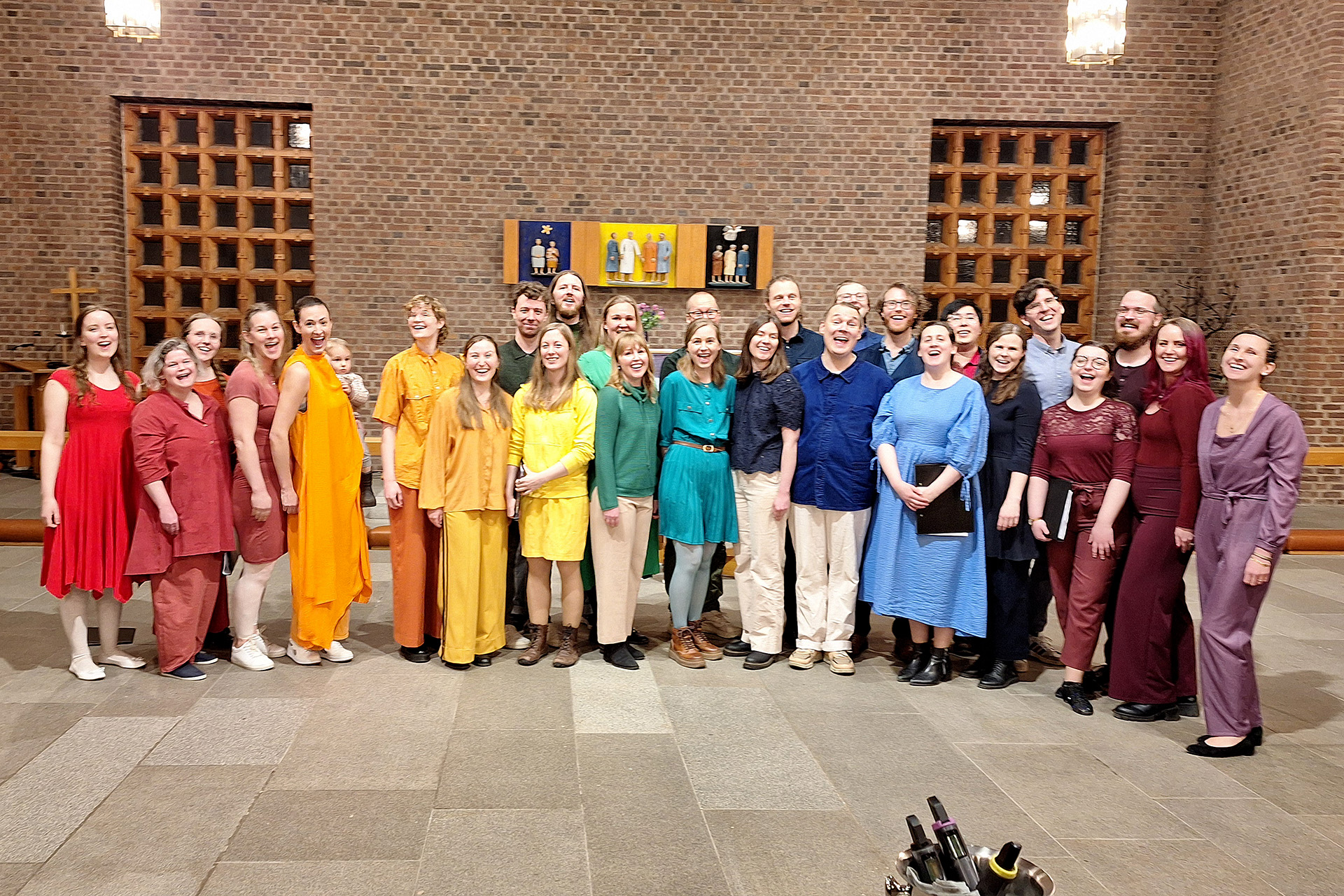 Glada körsångare klädda i regnbågens färger. 