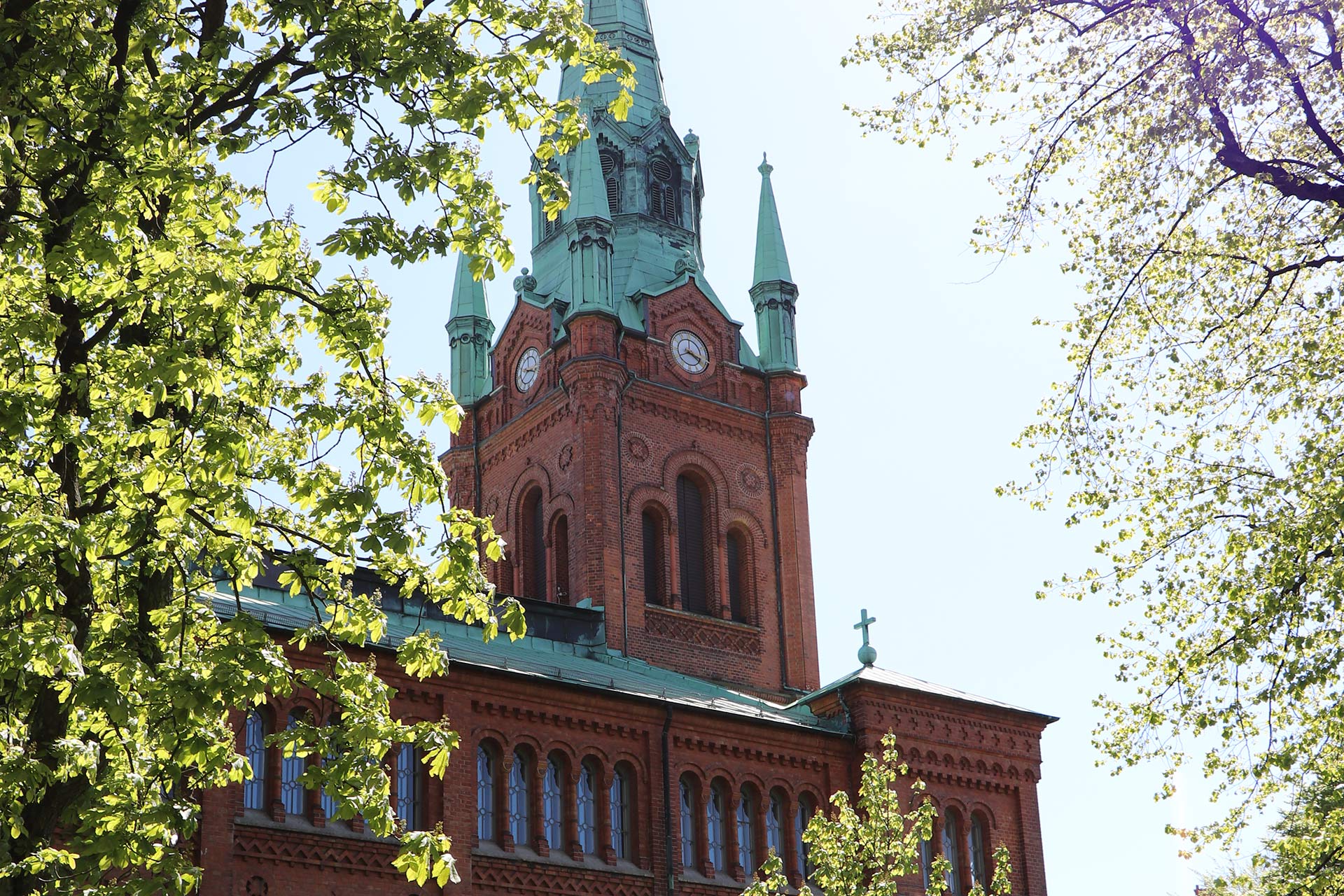 En tegelkyrka omramad av grönskande träd.