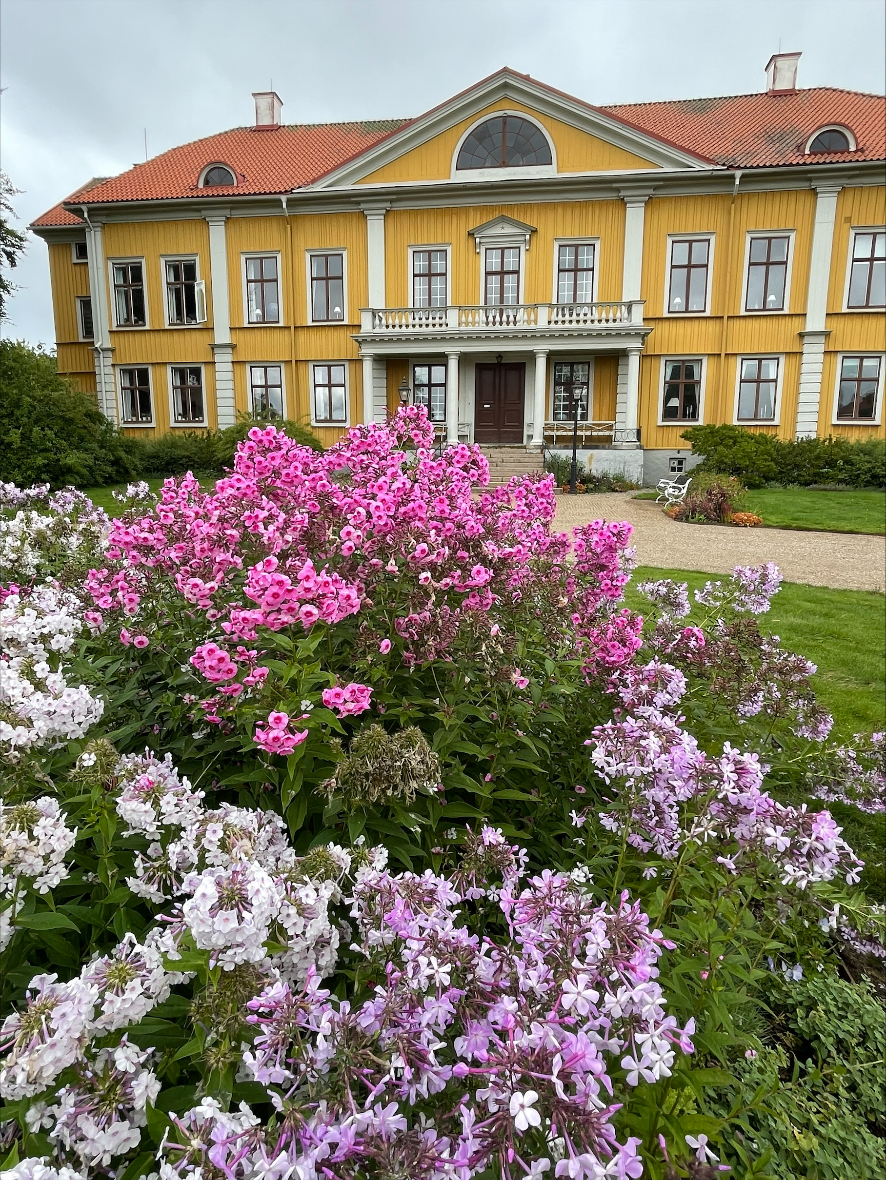 Biskopsgården Östrabo, med rosa sommarblommor i förgrunden.