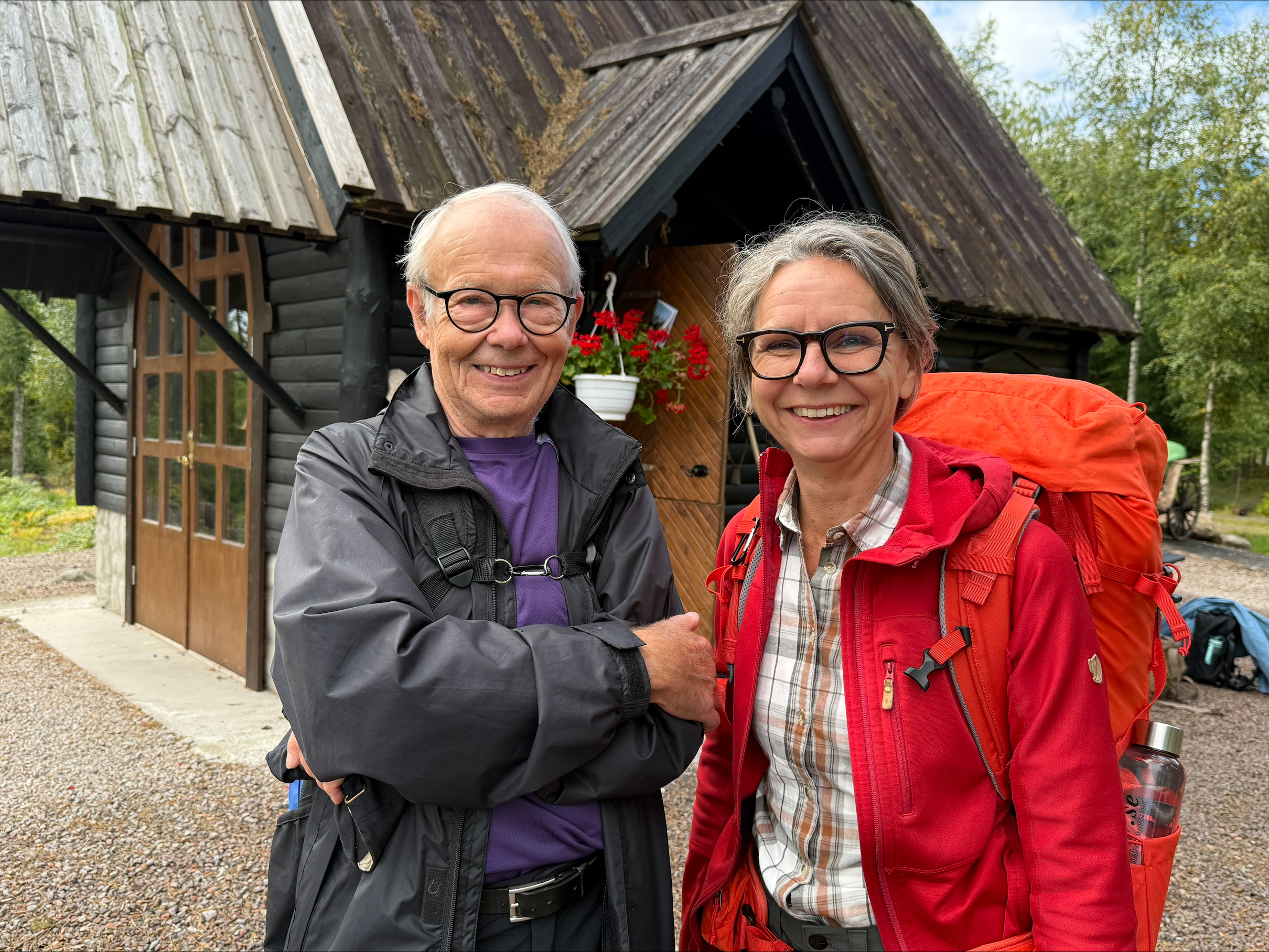 Halvfigursbild på en man och en kvinna, iklädda vindtäta ytterkläder och ryggsäckar, som ler mot kameran.