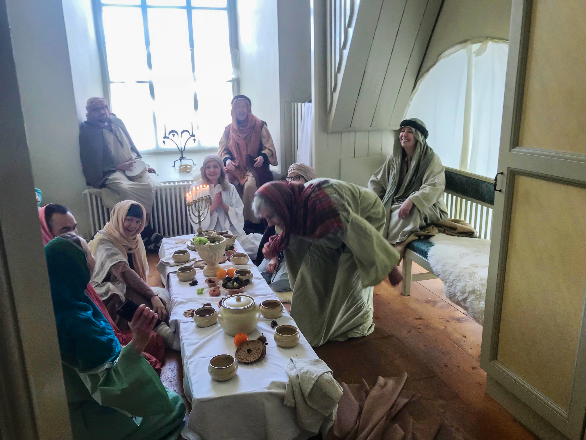 En grupp som sitter vid ett bord och är kädda i sjalar och kåpor och 