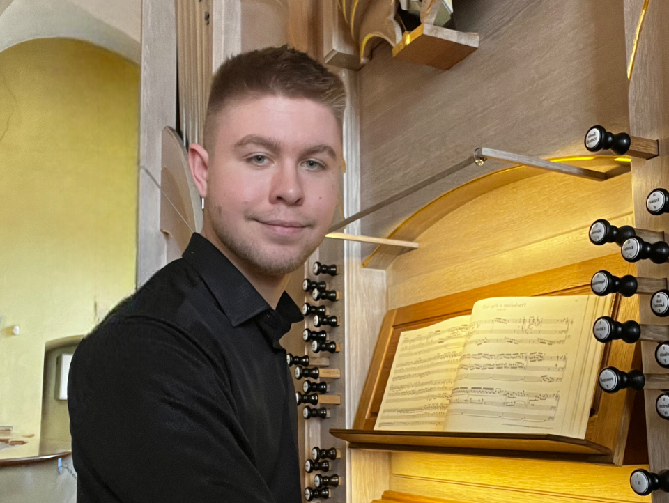 Fabian Gres i svart skjorta vid kyrkorgel, med noter på notstället.