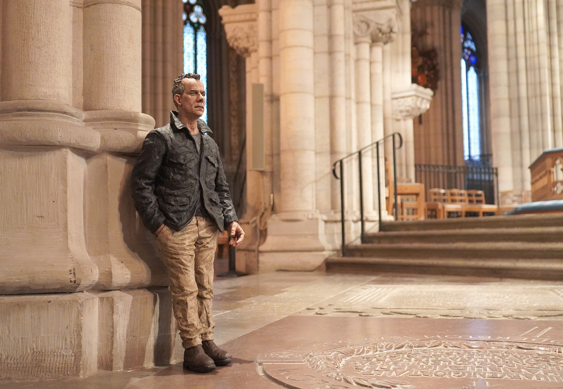 En av Sean Henrys naturtrogna bronsskulpturer i form av en man med grå jacka, beige byxor och fårat ansikte, placerad i domkyrkans högkor som en försmak av den utställning som kommer att visas sommaren 2026.