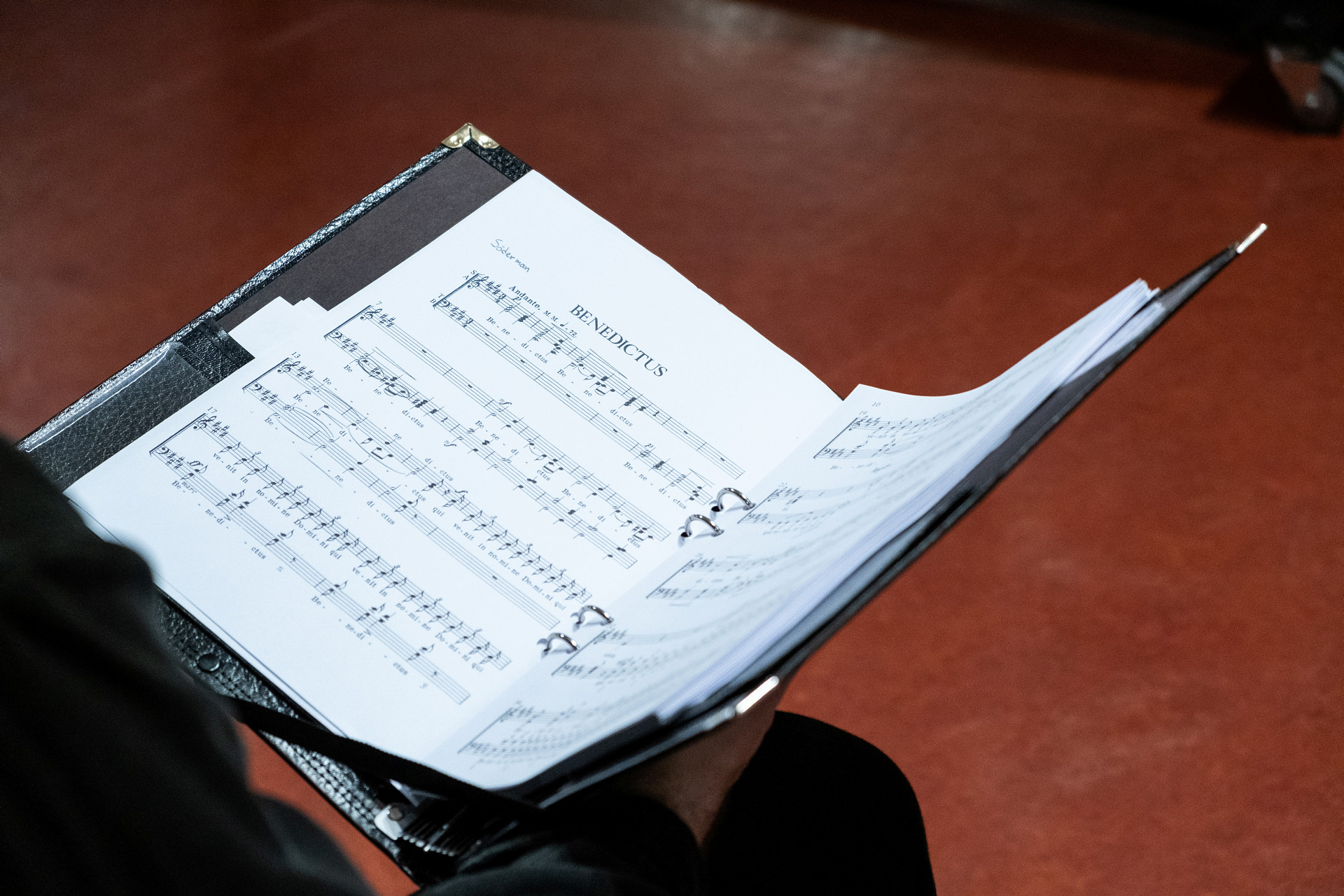 En person sitter med en pärm med noter i knät