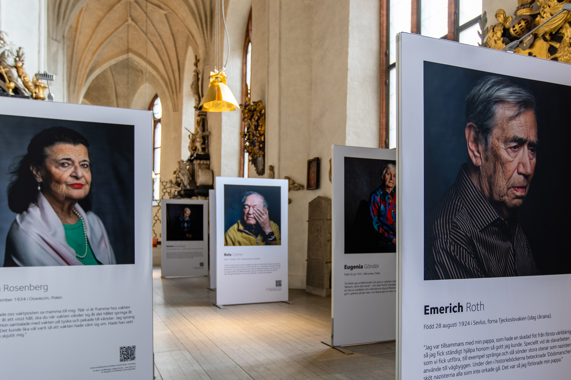 Vy över skärmar med foton av överlevare från Förintelsen.