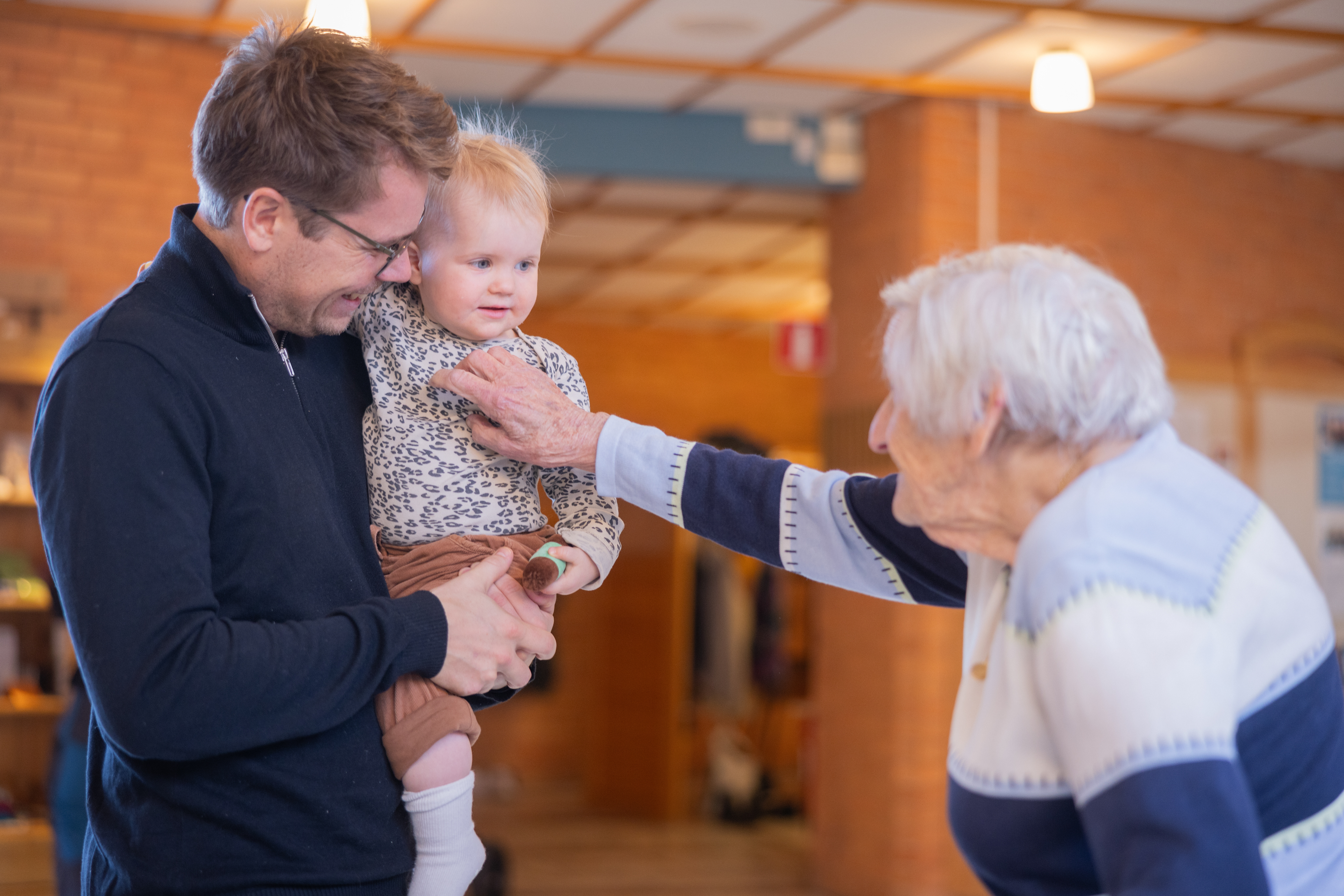 en pappa med ett barn som hälsar på äldre kvinna