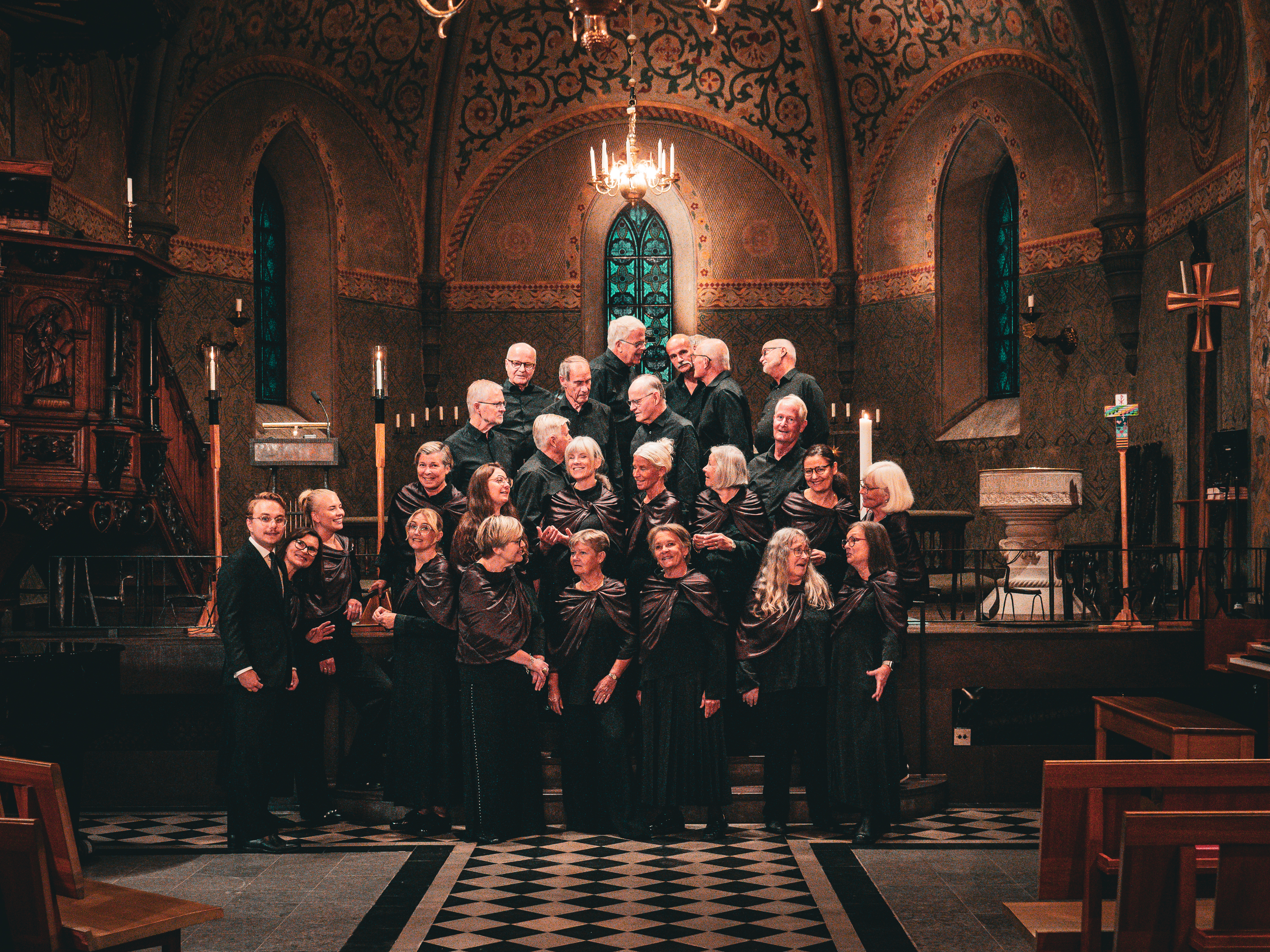 En grupp människor står i en kyrka. De flesta pratar med varandra, några tittar in i kameran och ler.