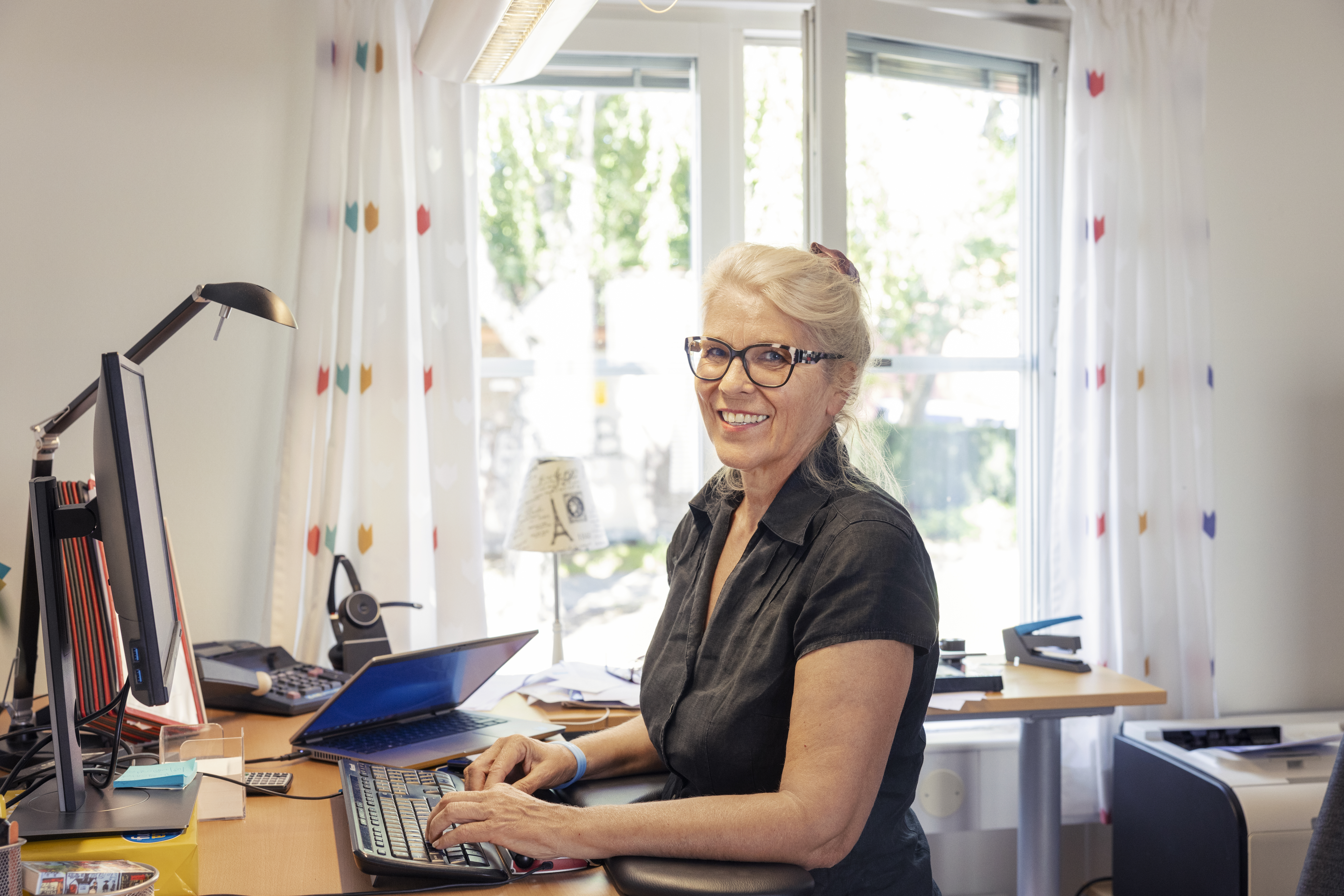 Kvinna står vid kontorsbord och arbetar