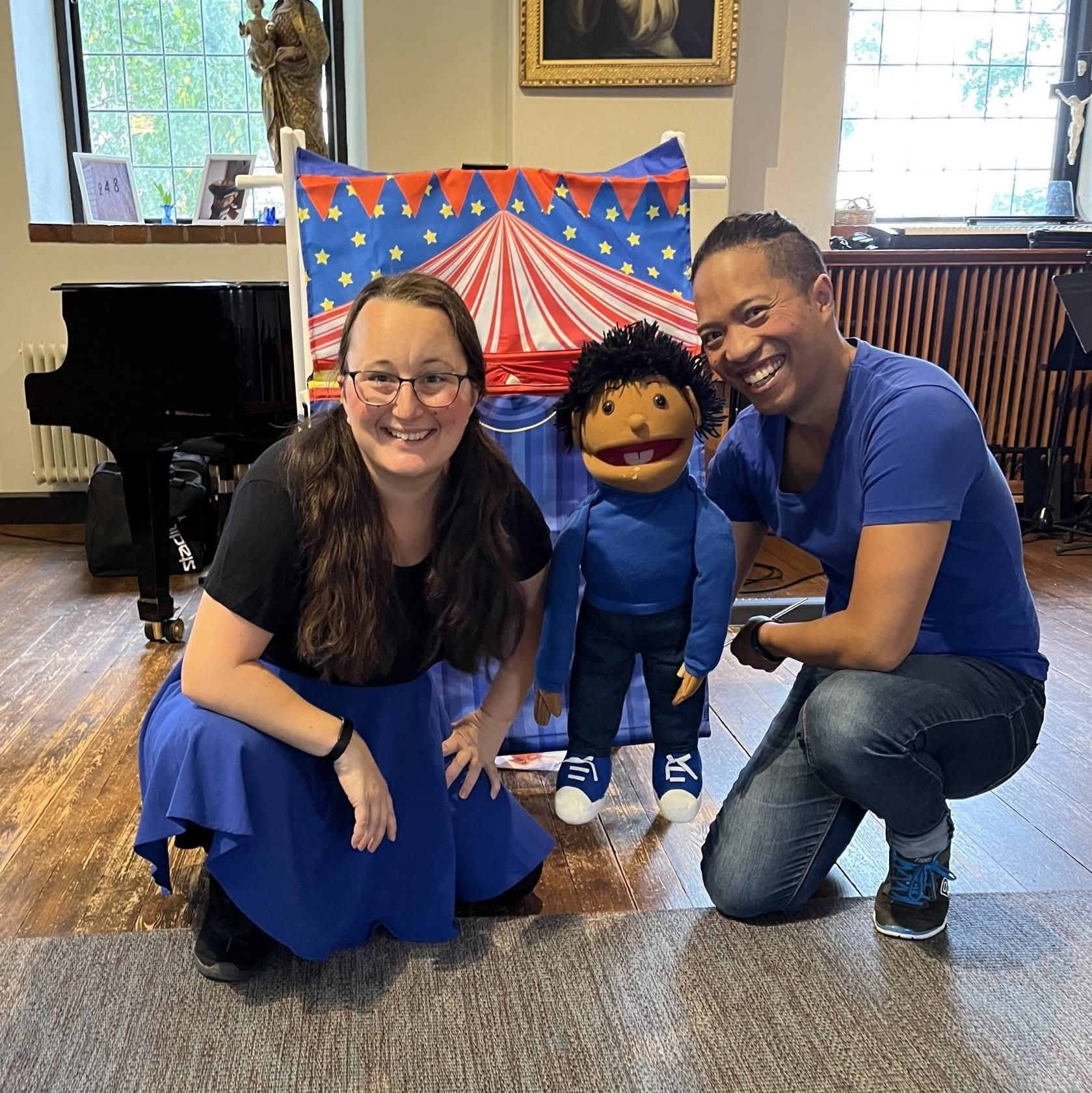 Två personer och en docka framför ett leksaksteatertält