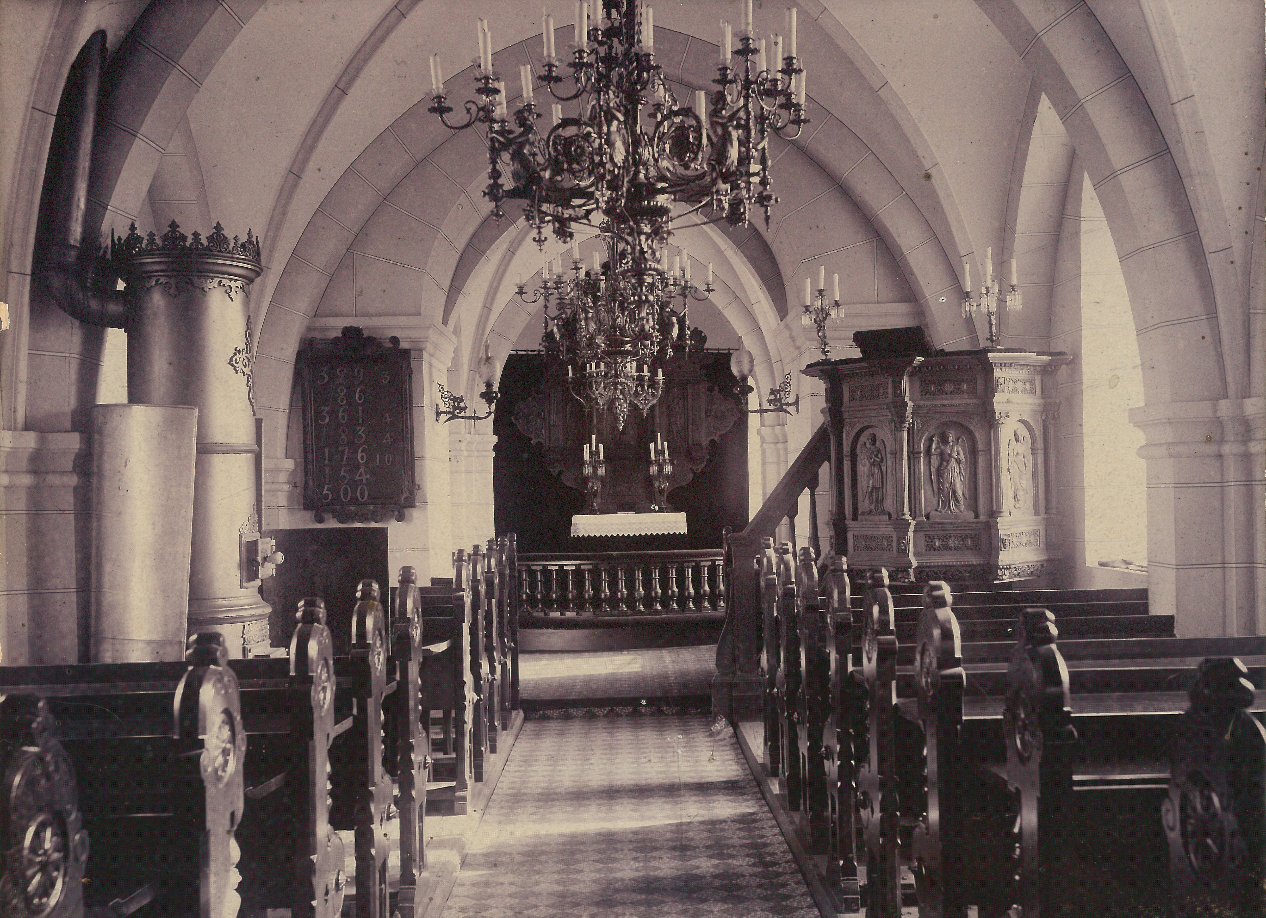 Brågarps kyrka invändigt med kamin vid norrväggen, predikstolen vid söderväggen, stor altaruppsats och bänkar i mörkt trä.