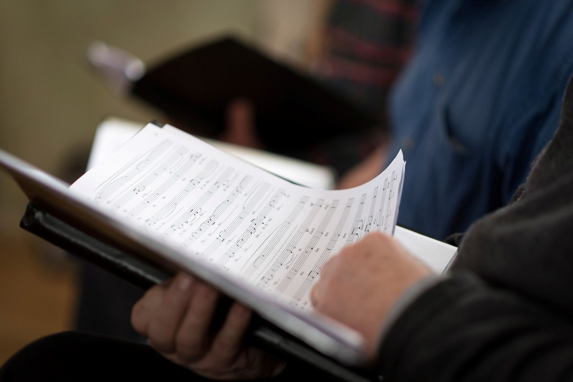 En person sitter och bläddrar i en pärm med noter