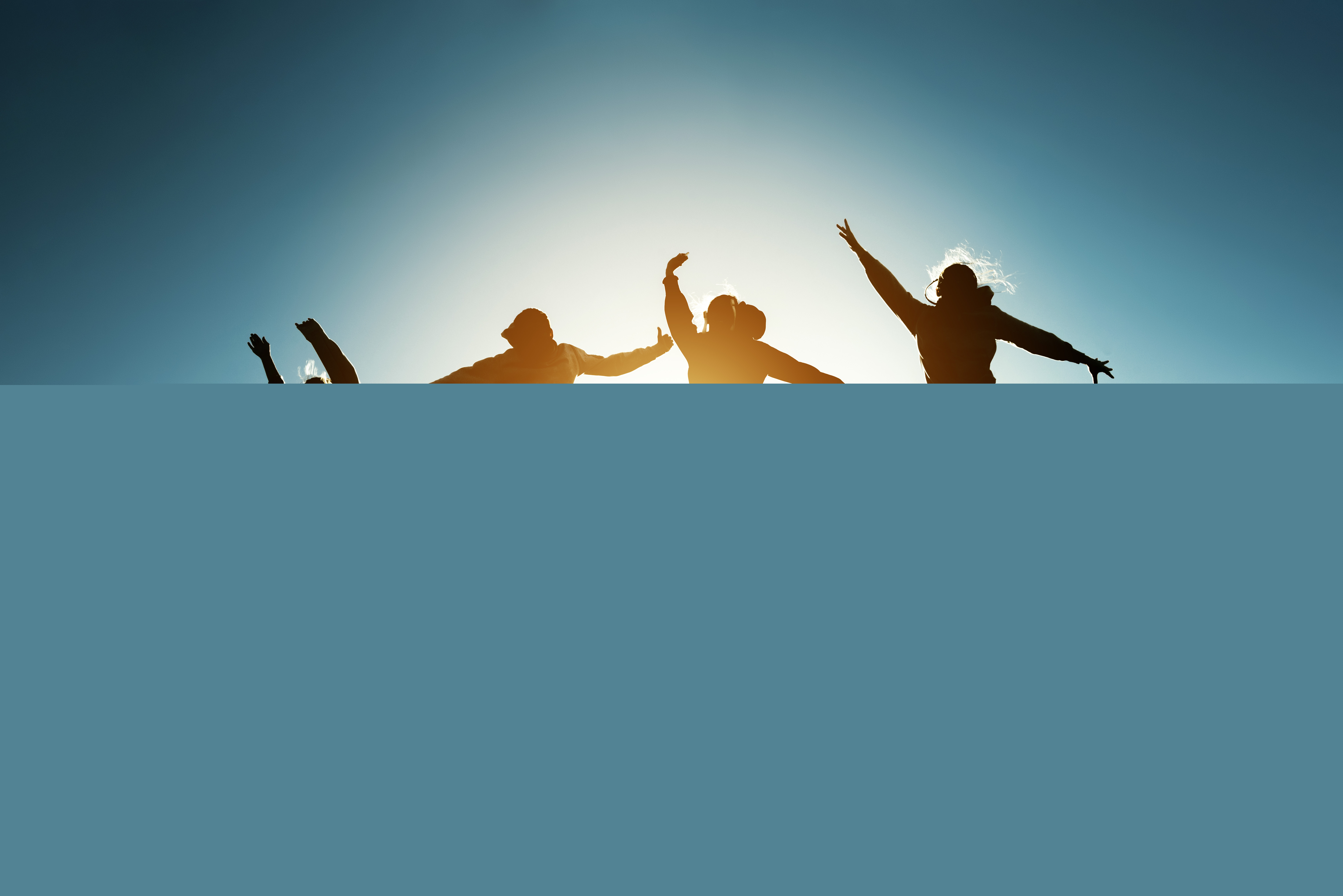 Tonåringar som hoppar, de syns enbart som siluetter mot en ljus himmel.