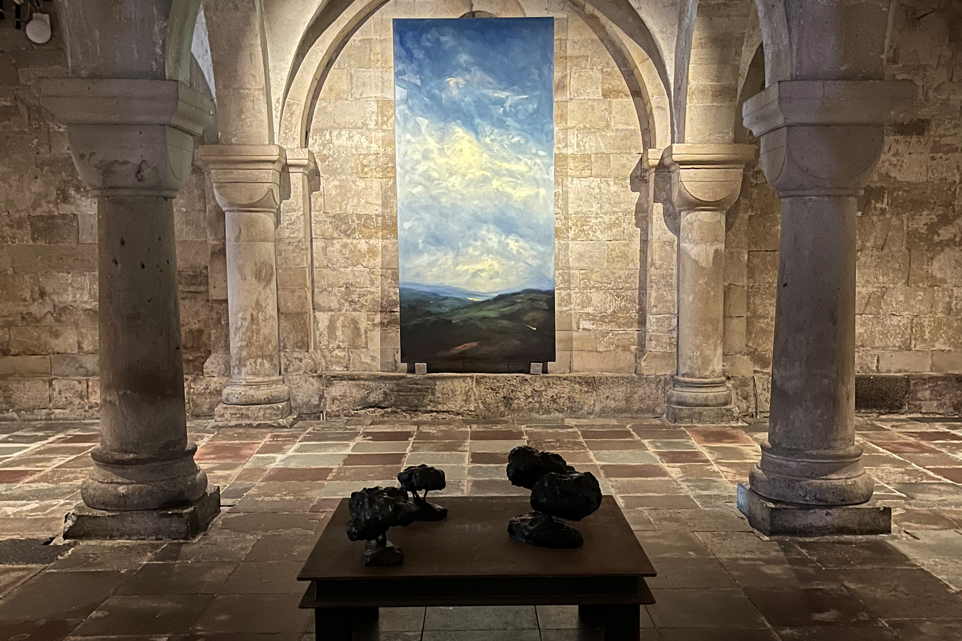 En målningmed ett böljande landskap och molning himmer på en av kryptans väggar.