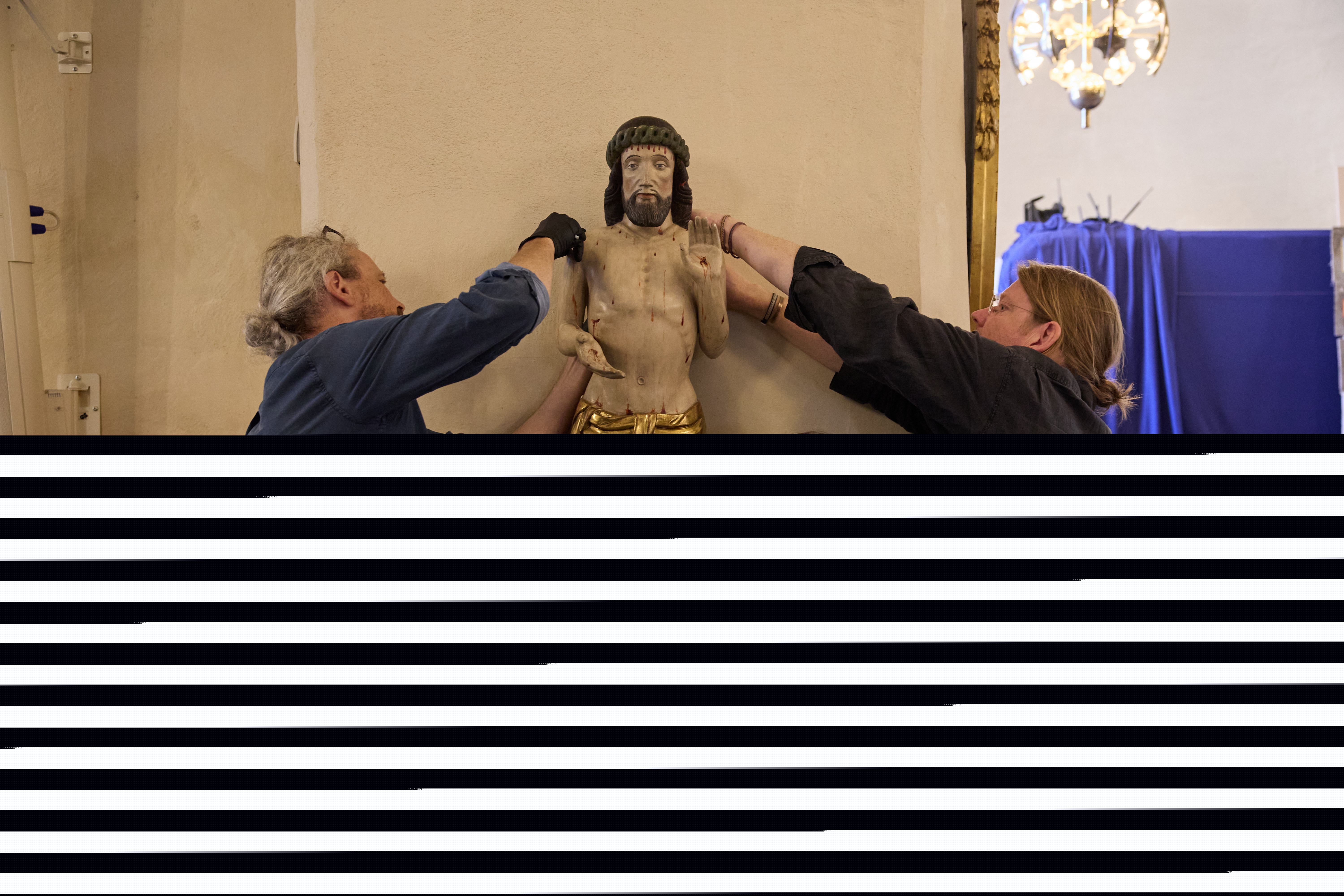 Tree personer håller i Jesus som träskulptur