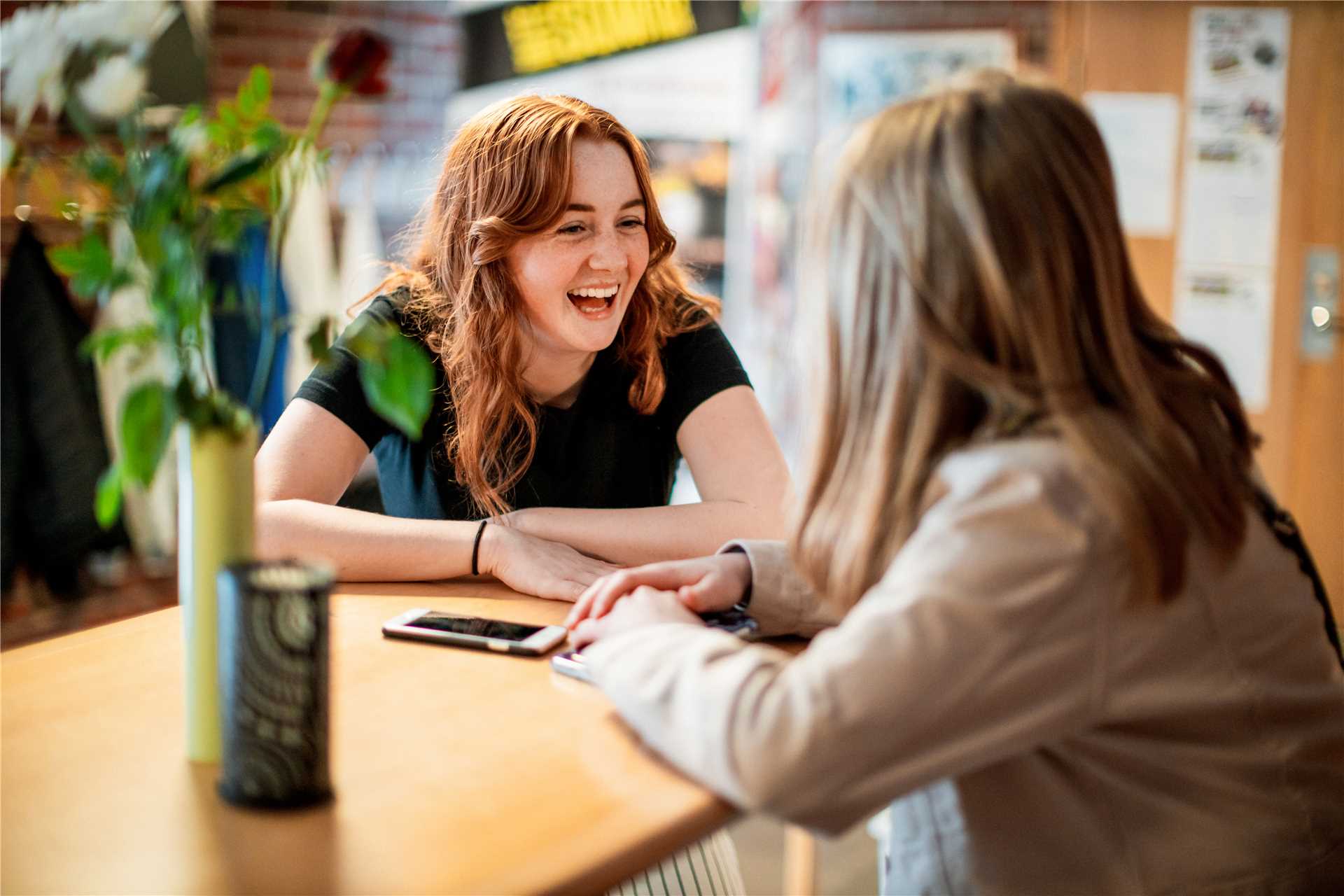 Två tjejer sittandes vid ett bord och skrattar