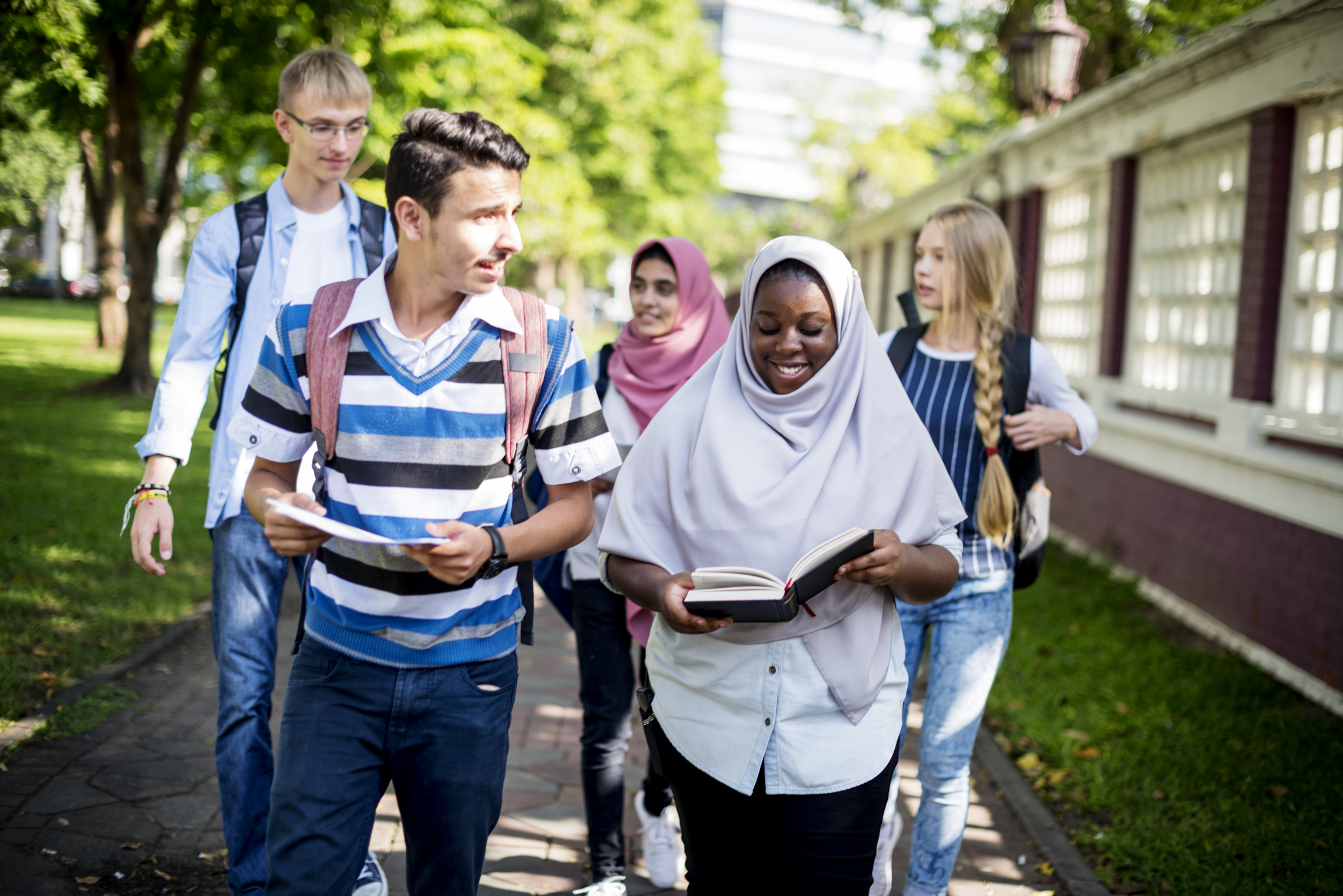 En grupp med ungdomar med olika hudfärg och hårfärg, några iklädda slöja, går och pratar tillsammans.