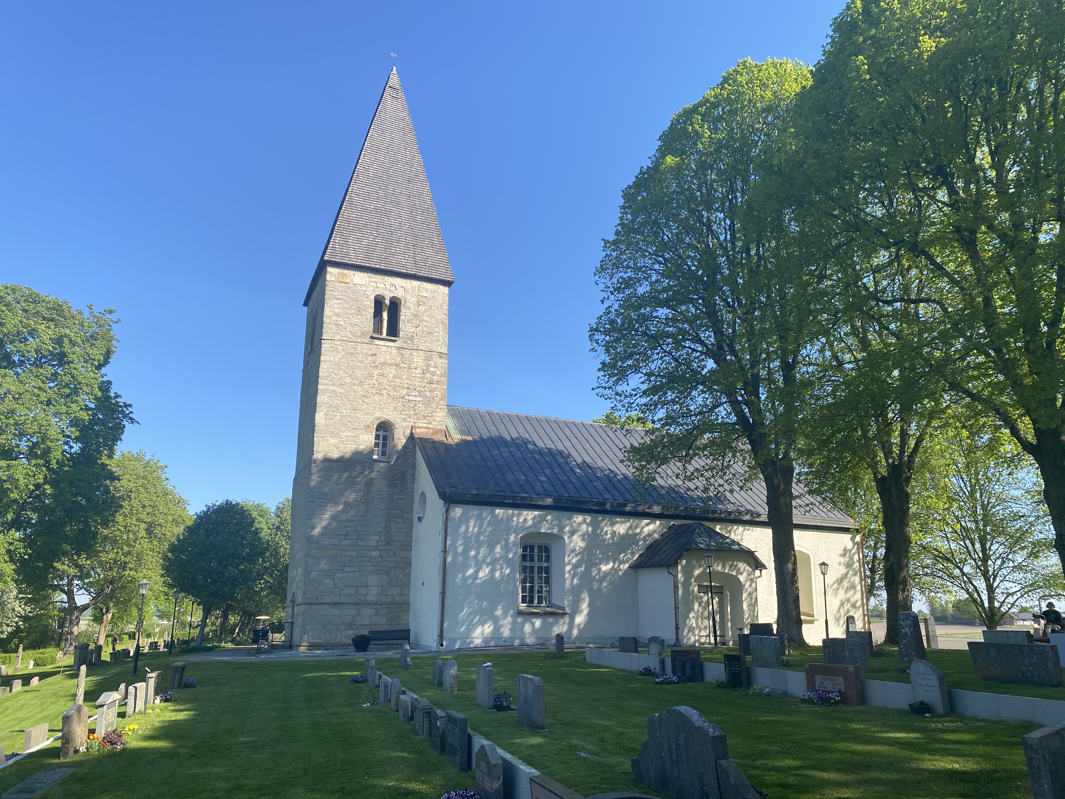 Hardemo kyrka omgiven av grönskande träd.