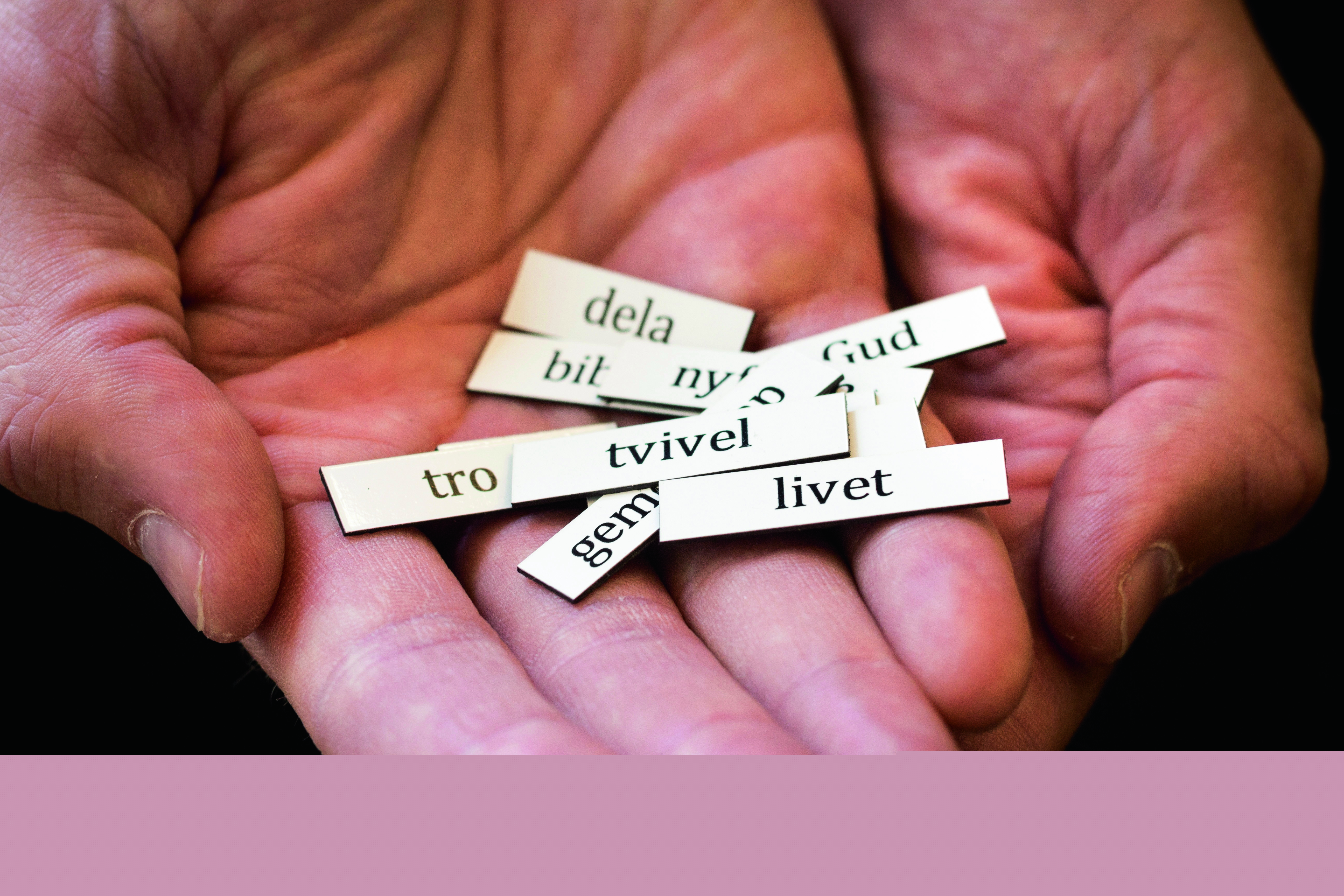 Tbå öppna händer med ordlappar som det står "tro", "tvivel", "livet" på.