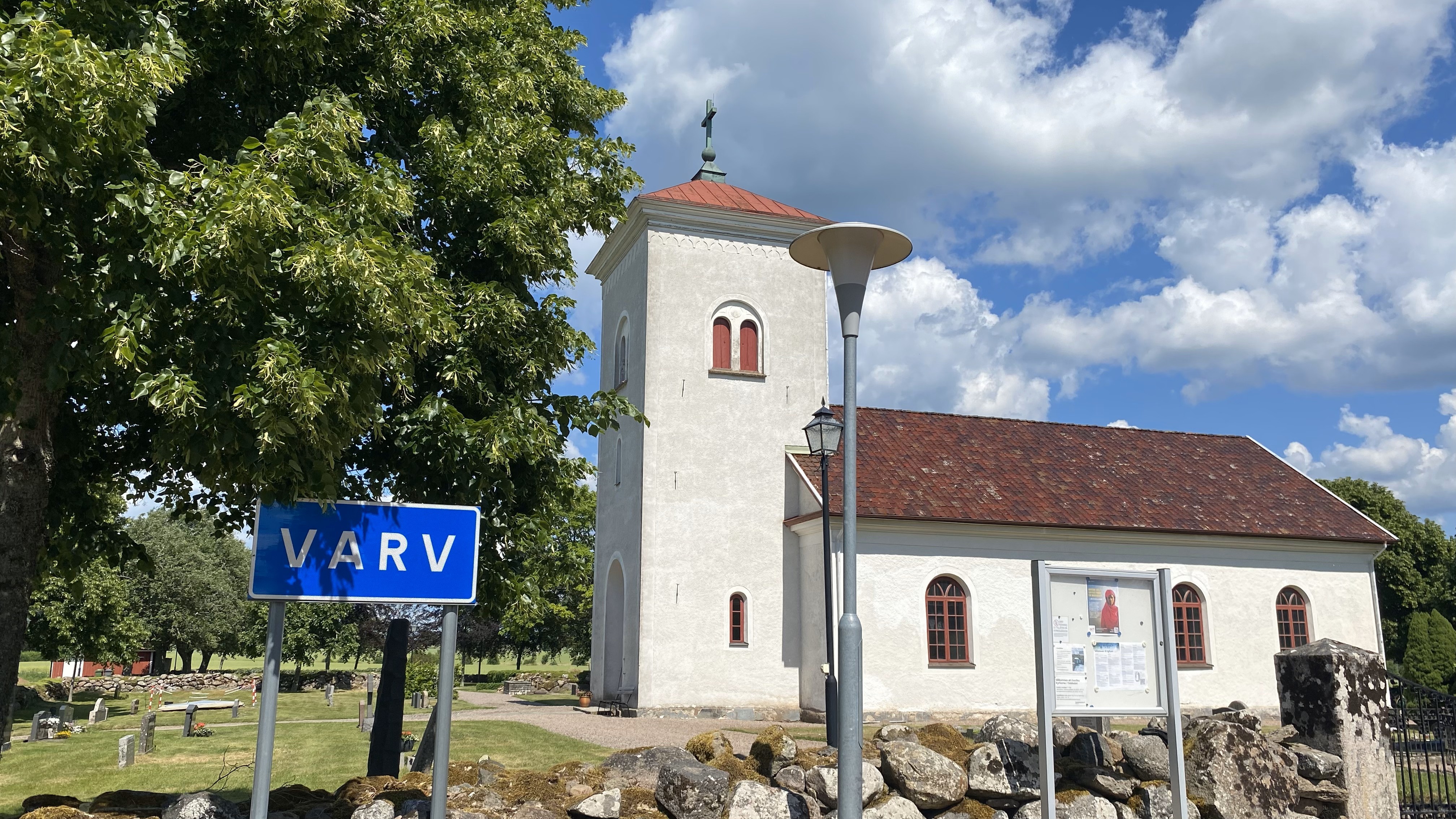 En vitputsad kyrka, bredvid en vägskylt där det står "Varv."
