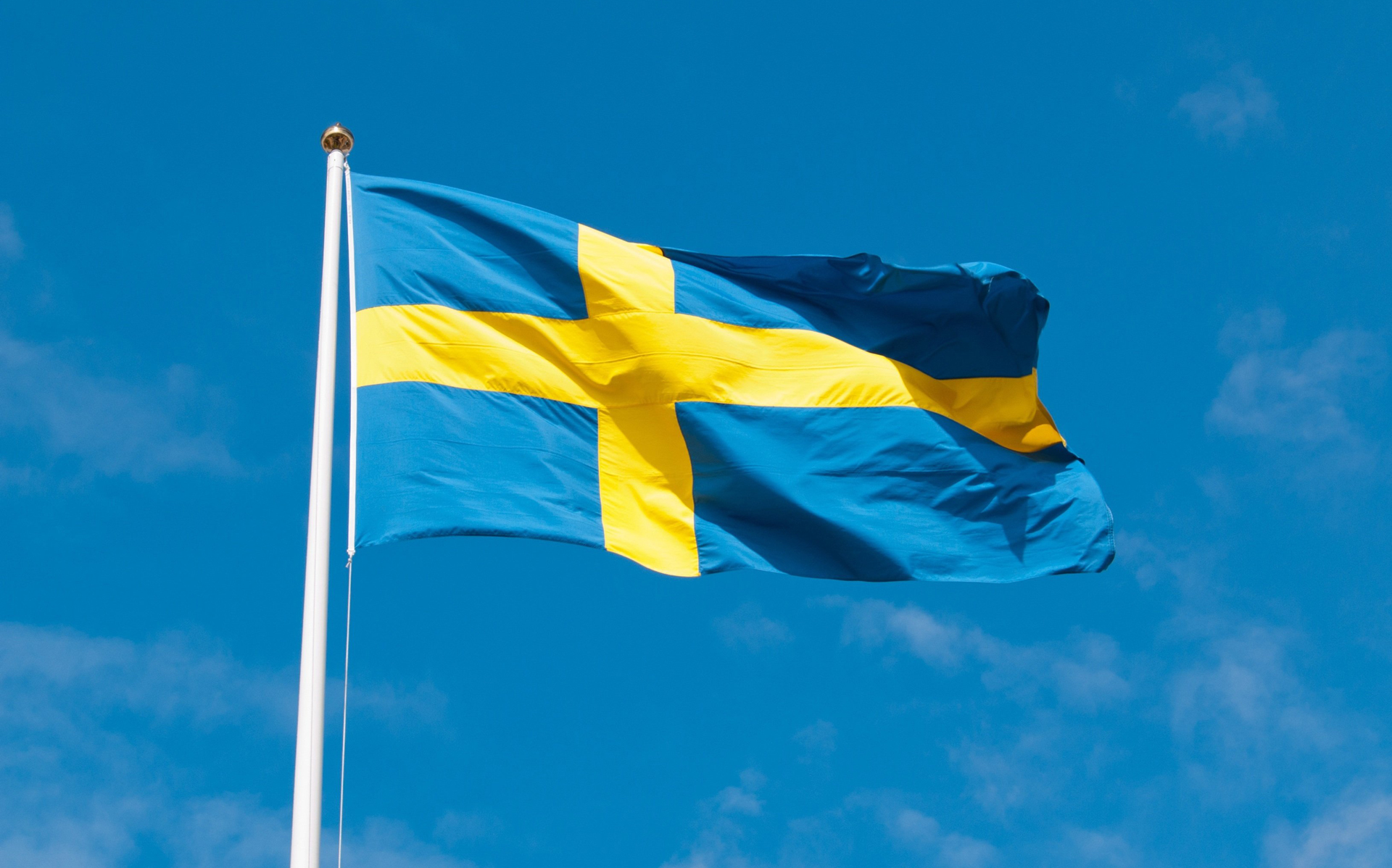 Svenska flaggan vajar mot blå himmel.