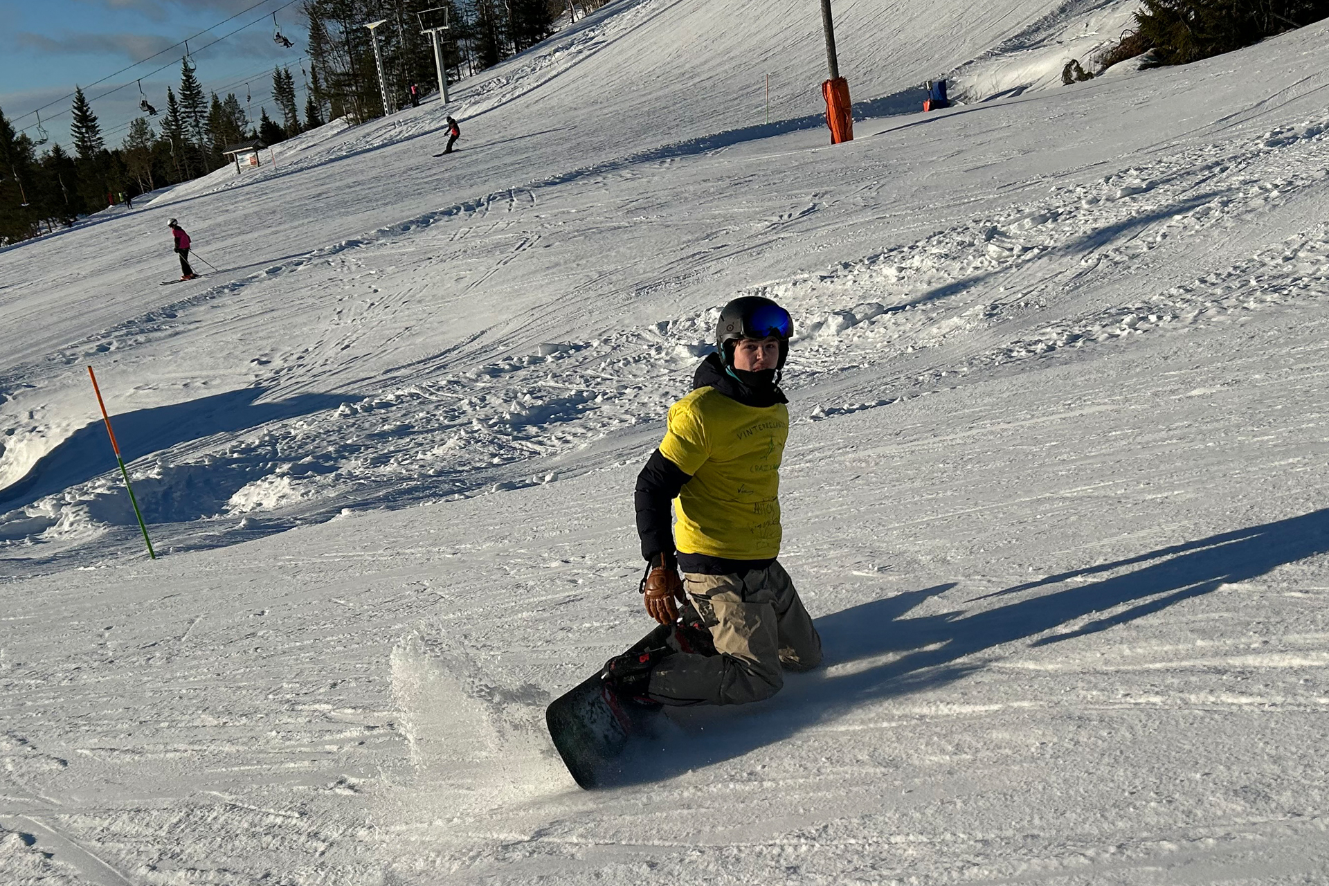 En person åker snowboard i en skidbacke. 