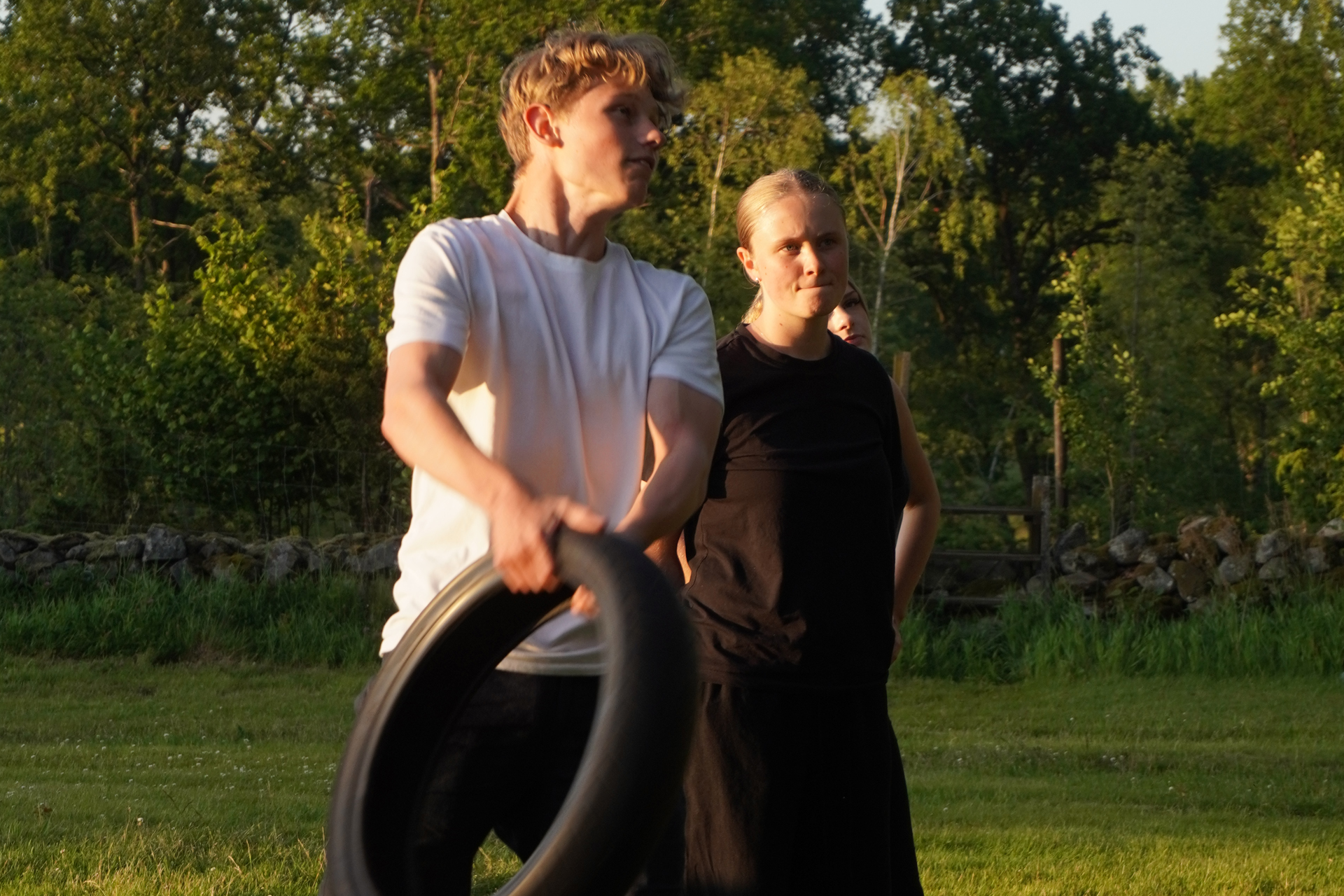 En kille och en tjej står på en gräsmatta och håller i ett däck.