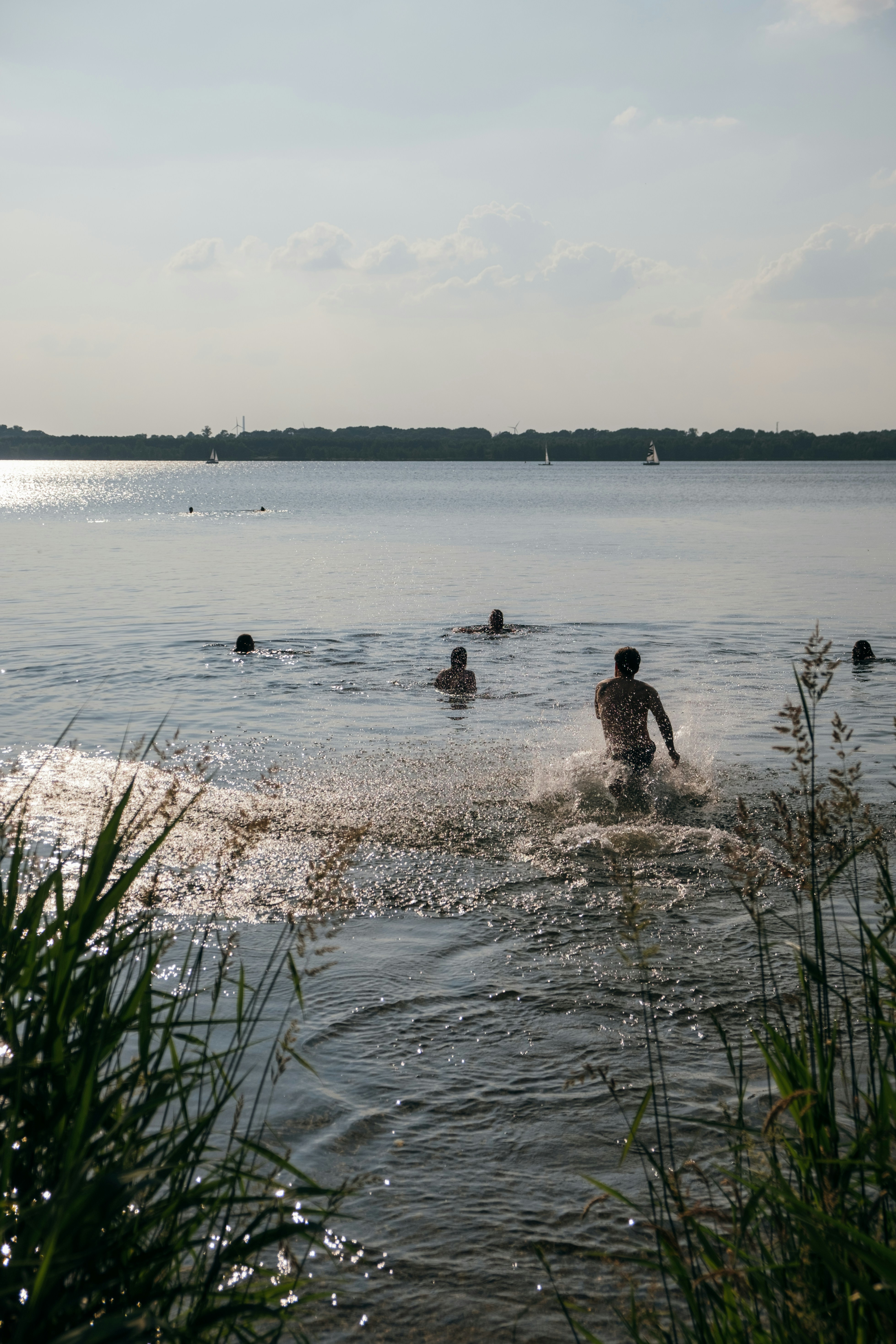Fem ungdomar badar i ett solbelyst vattendrag. Det är sommar. 
