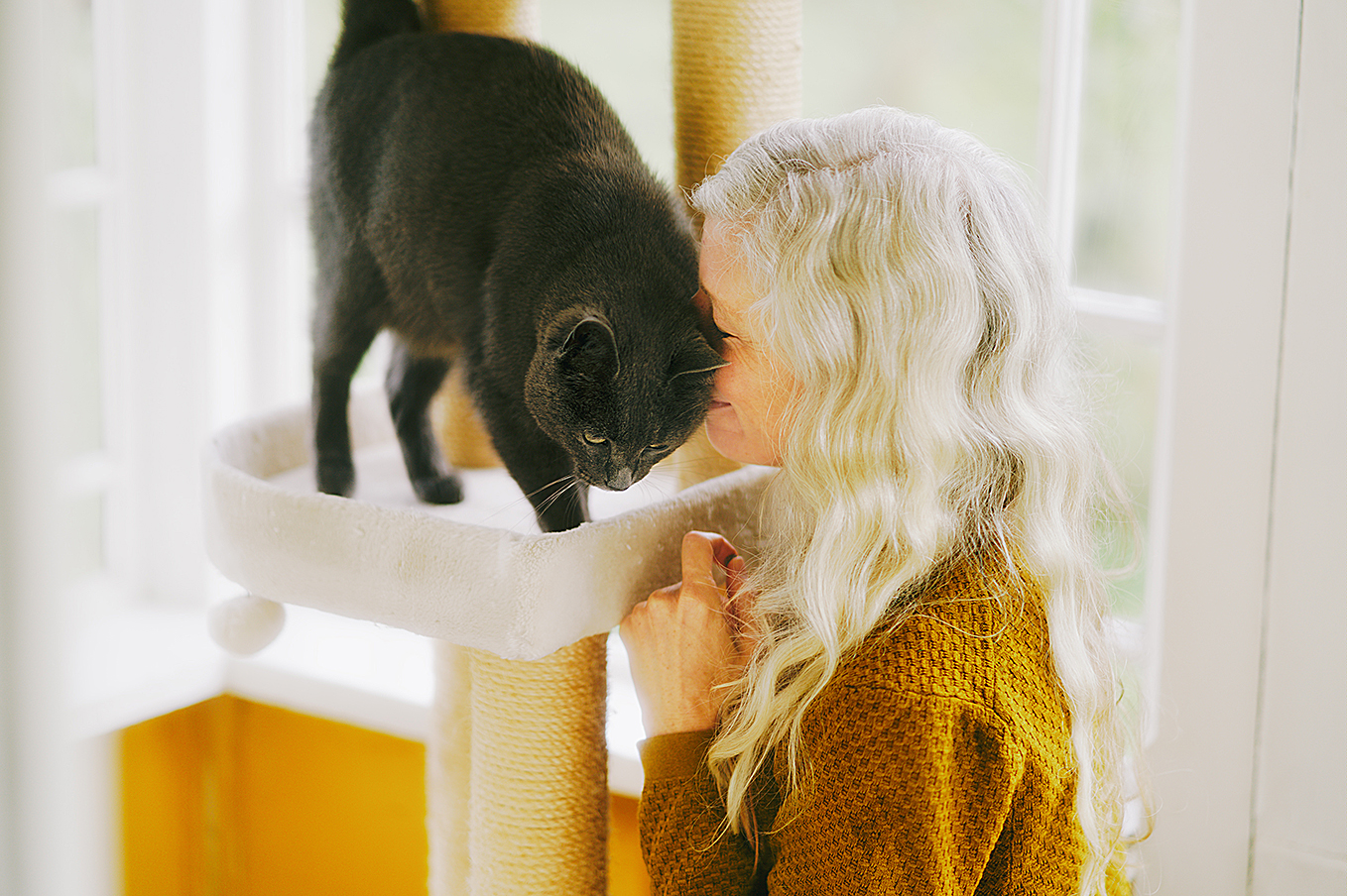 Charlotta Eriksson Molin gosar med sin katt som stryker sig mot hennes ansikte.