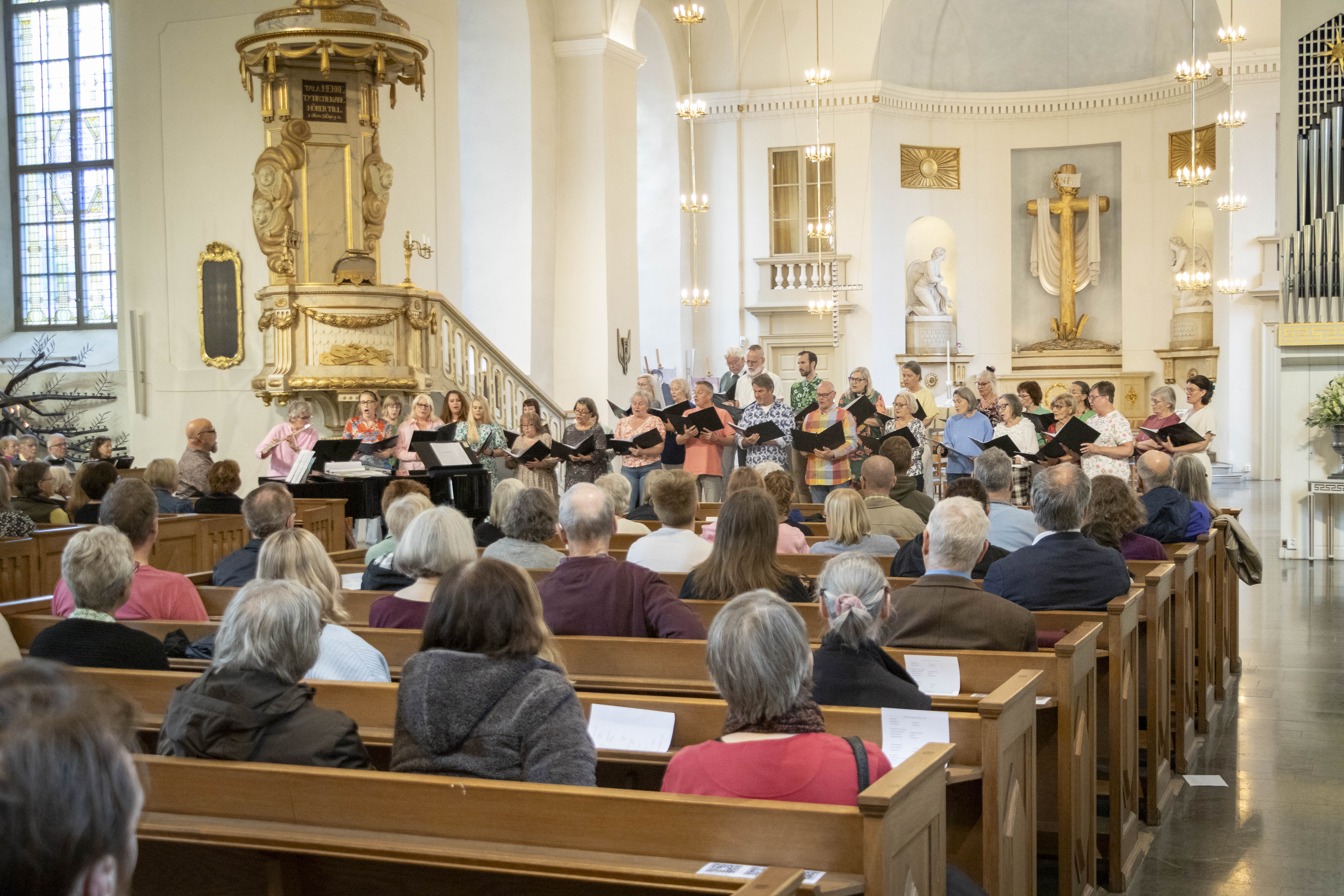 Ett trettiotal sångare sjunger med pianist i Karlstads domkyrka.
