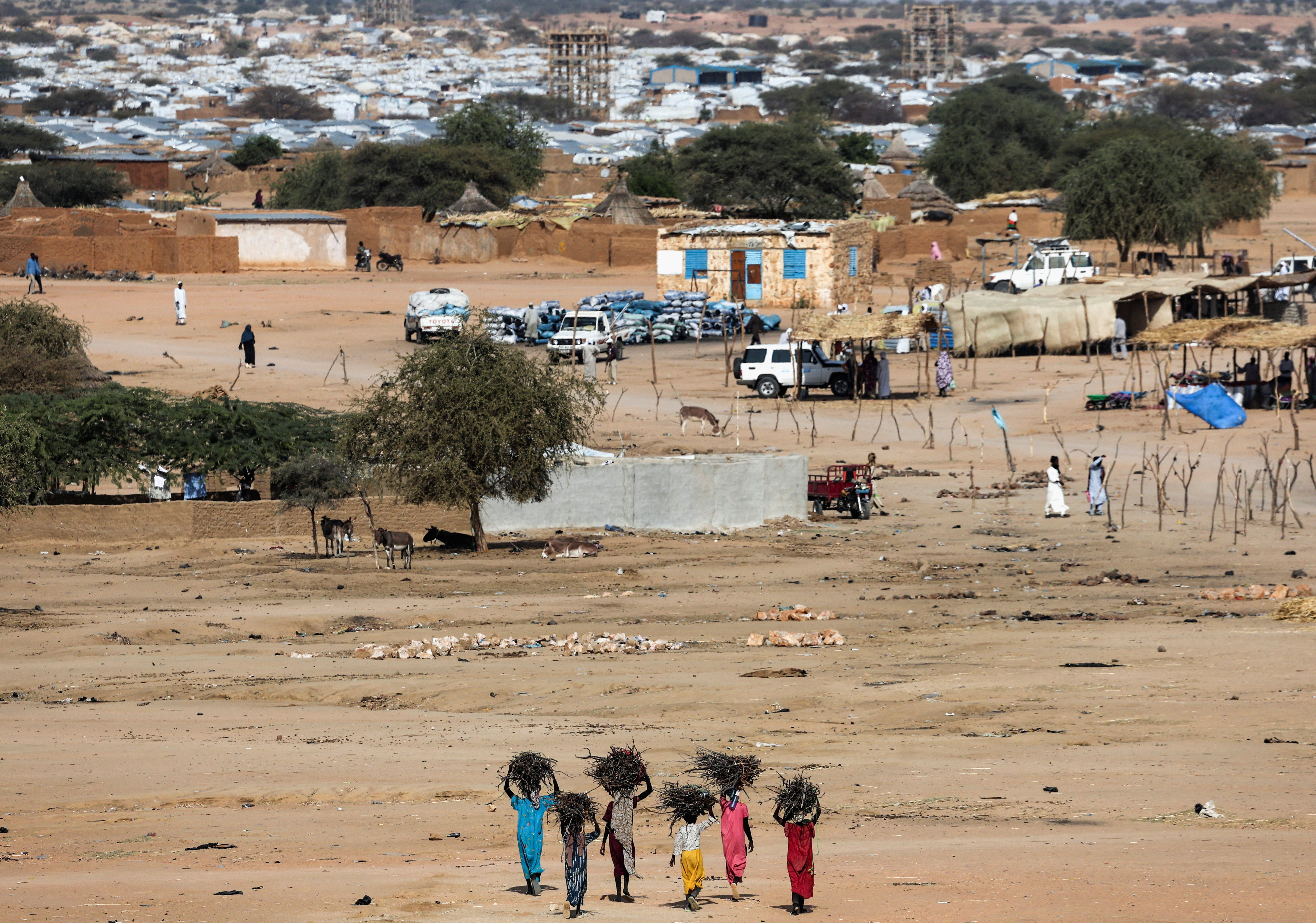 Kvinnor som går mot ett flyktingläger på avstånd