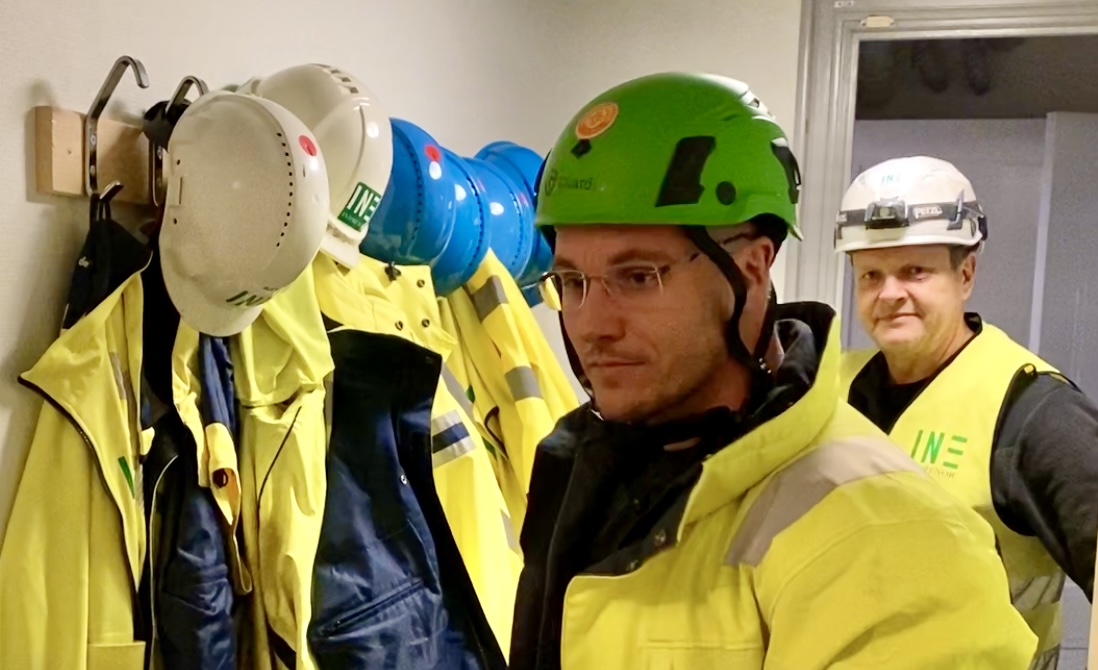 två personer bär skyddshjälm och varselväst