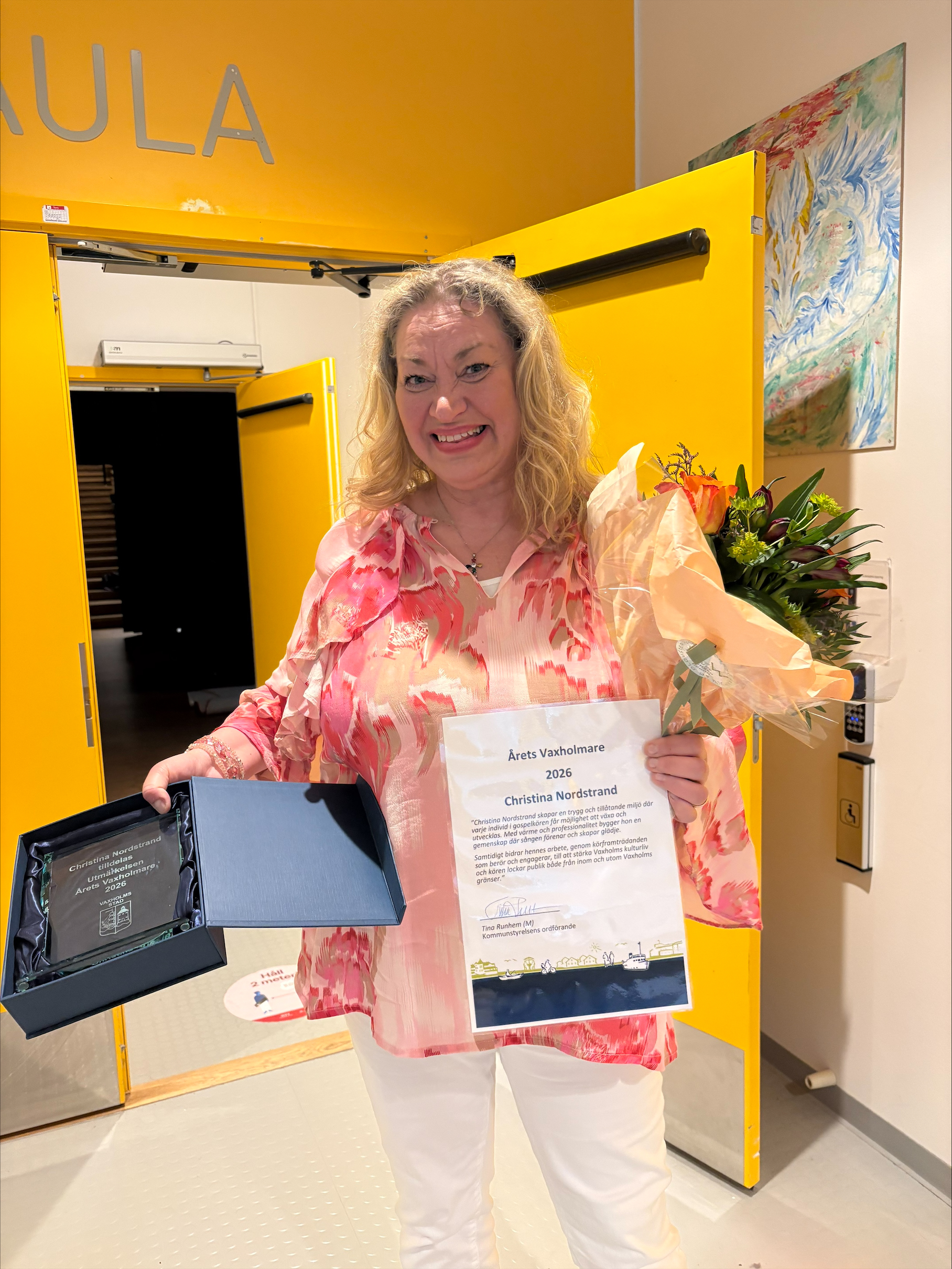 Christina Nordstrand som är gospelkörledare står med rosa blus, och har pris samt prismotivering i handen. Hon ser glad ut.