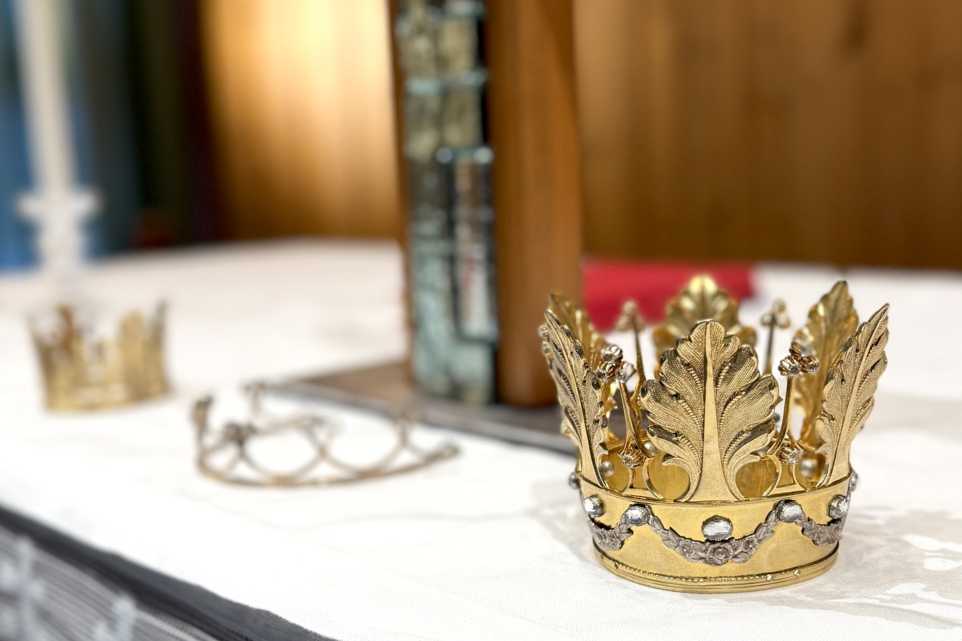 Bild på tre brudkronor vad av en i guld i fokus.