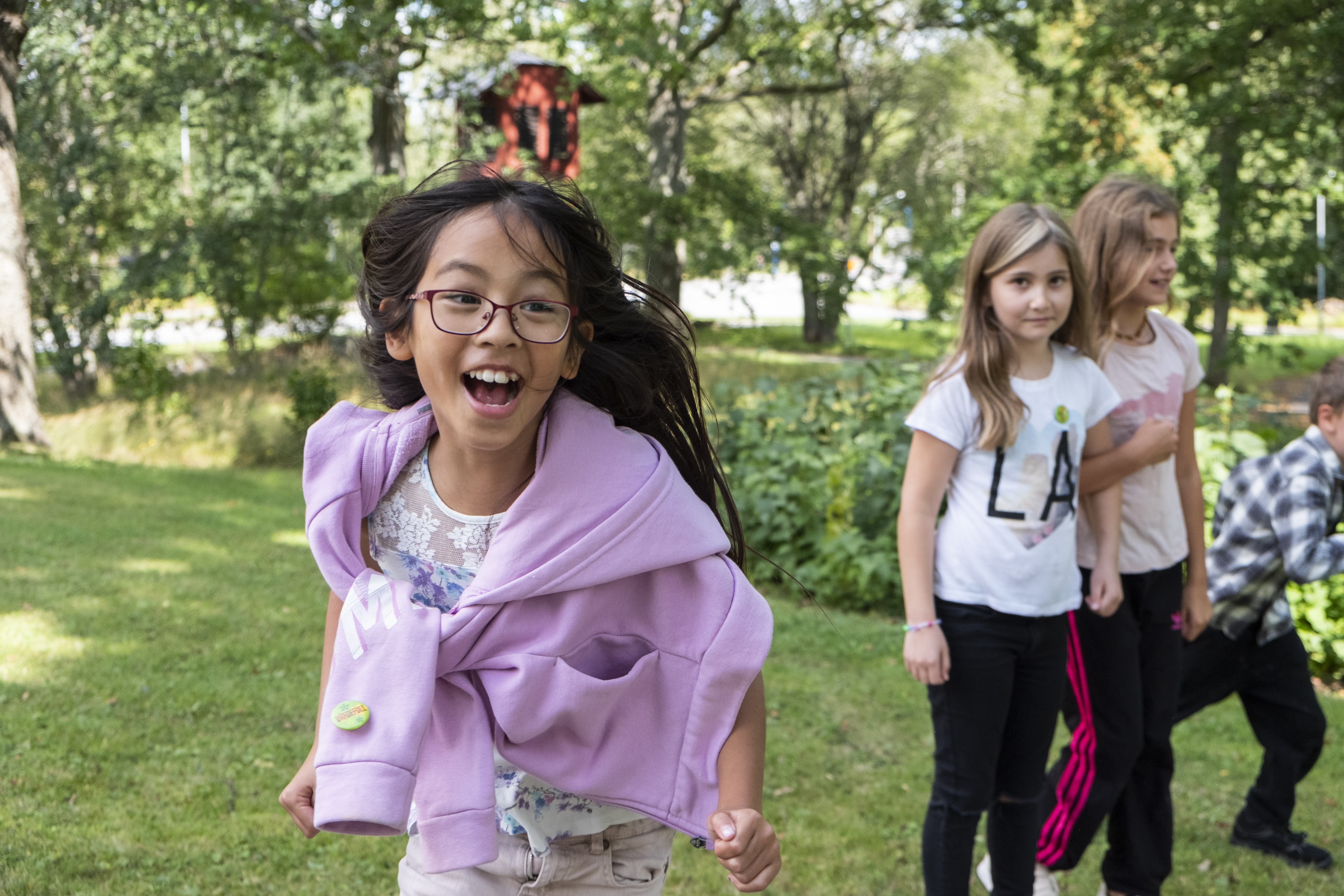Flicka med glasögon och lila tröja springer mot kameran