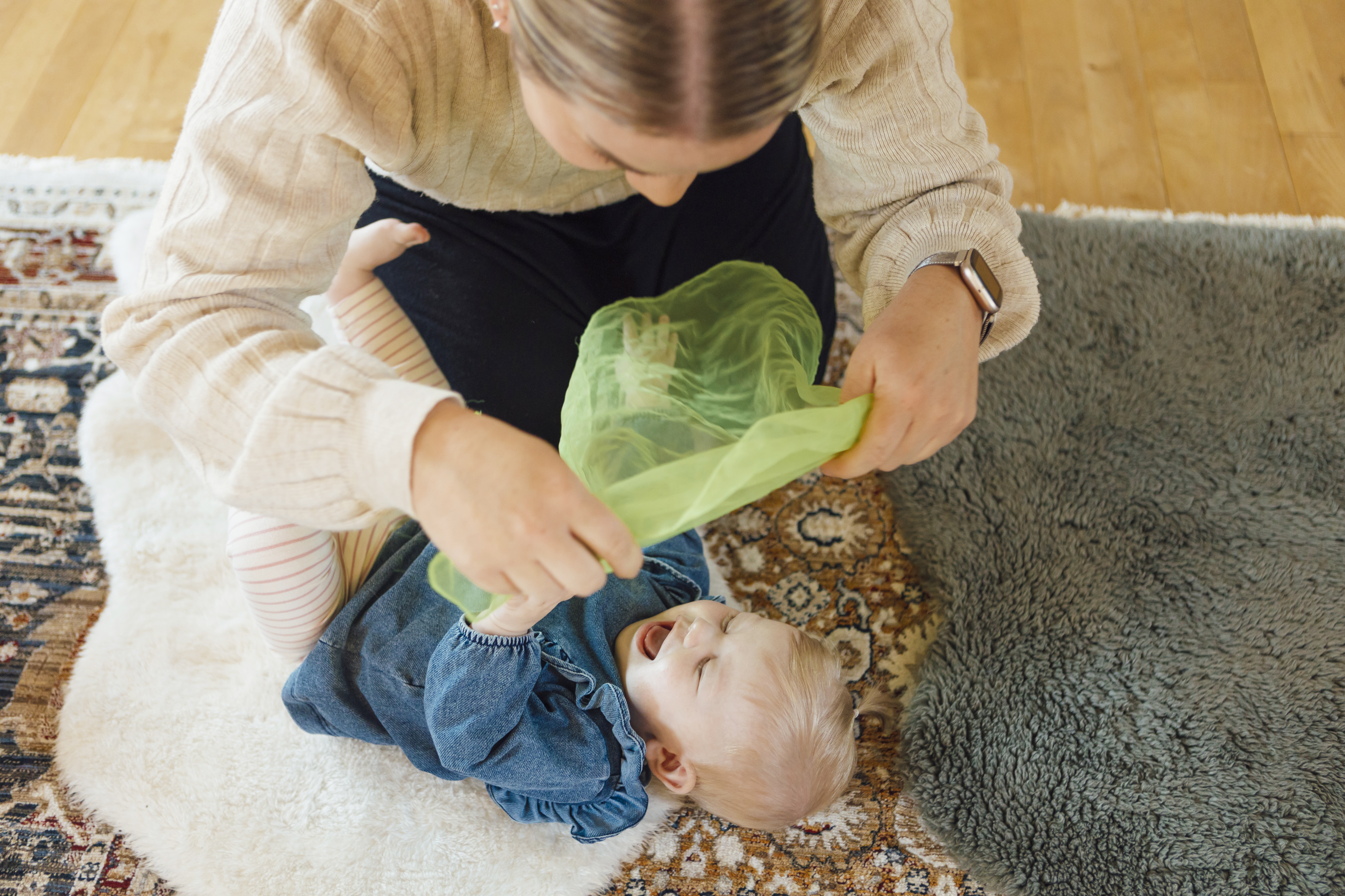 Mamma som använder en sjal för att leka tittut med sin bebis