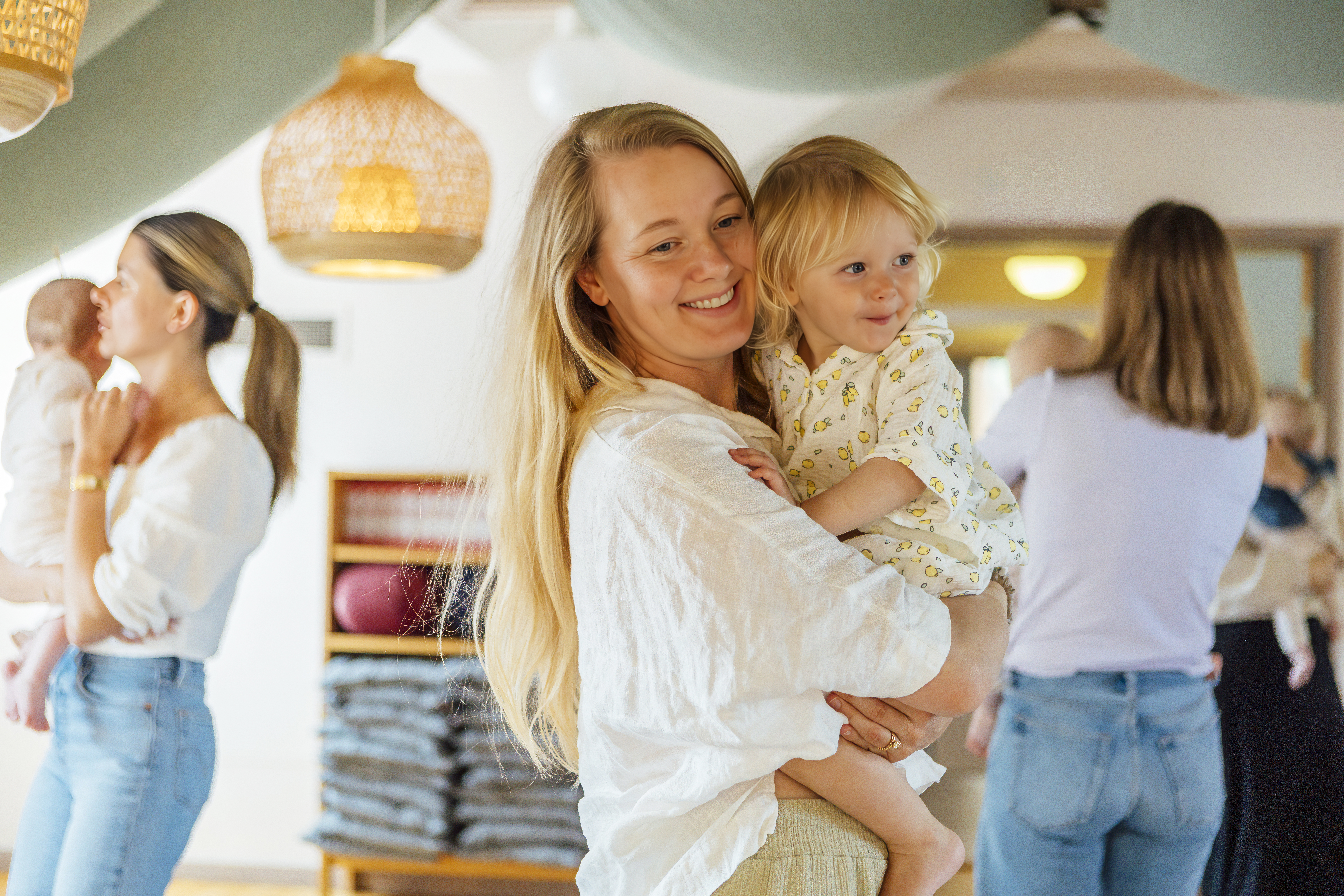 Mamma som bär sitt barn i famnen under barnverksamhet