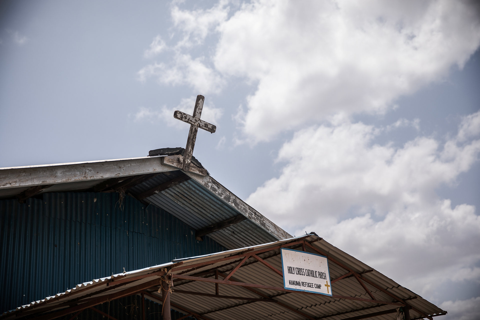 Ett kors på kyrktak mot blå himmel 