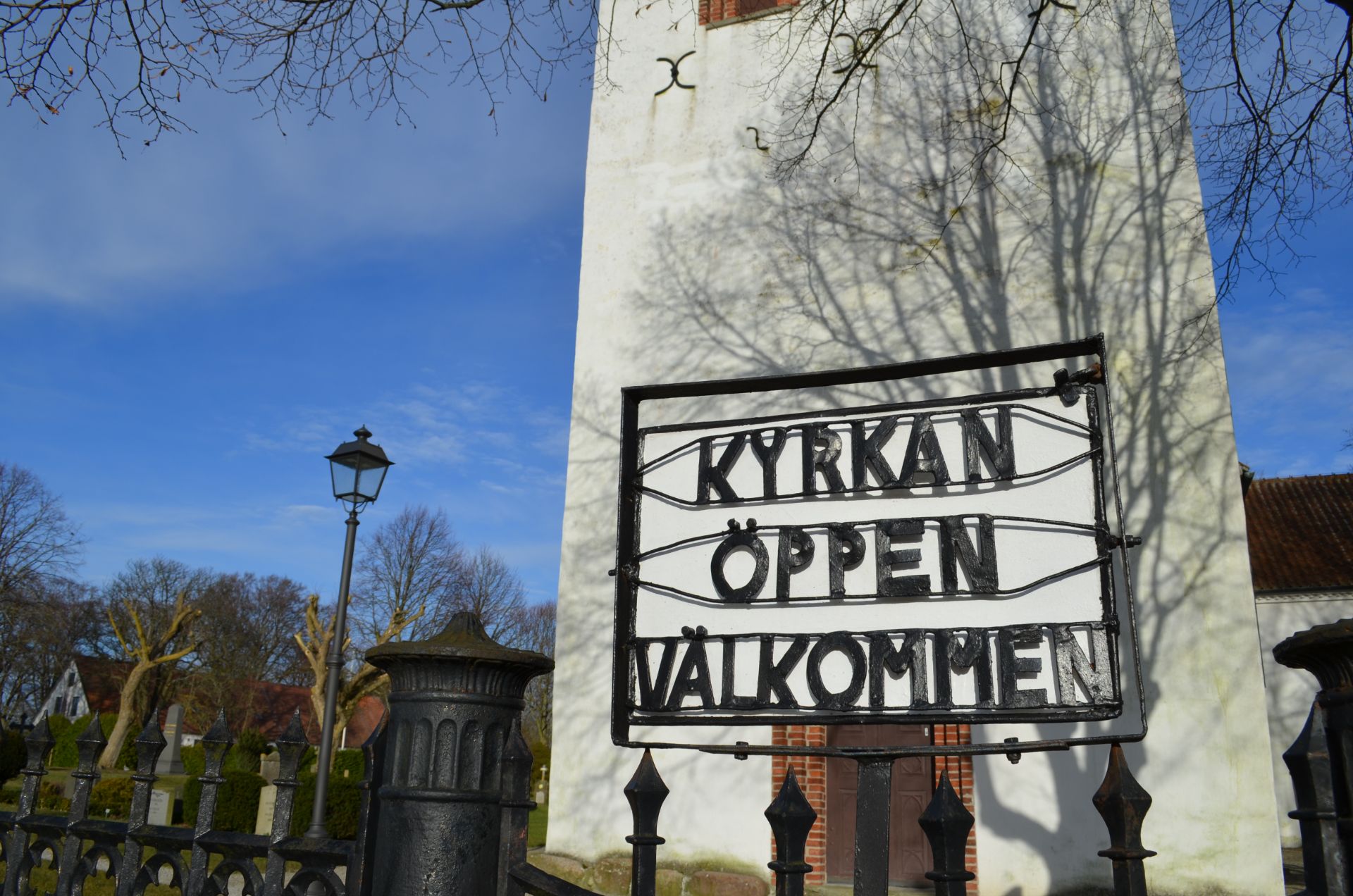 Smidesskylt utanför Igelösa kyrka med texten Kyrkan öppen