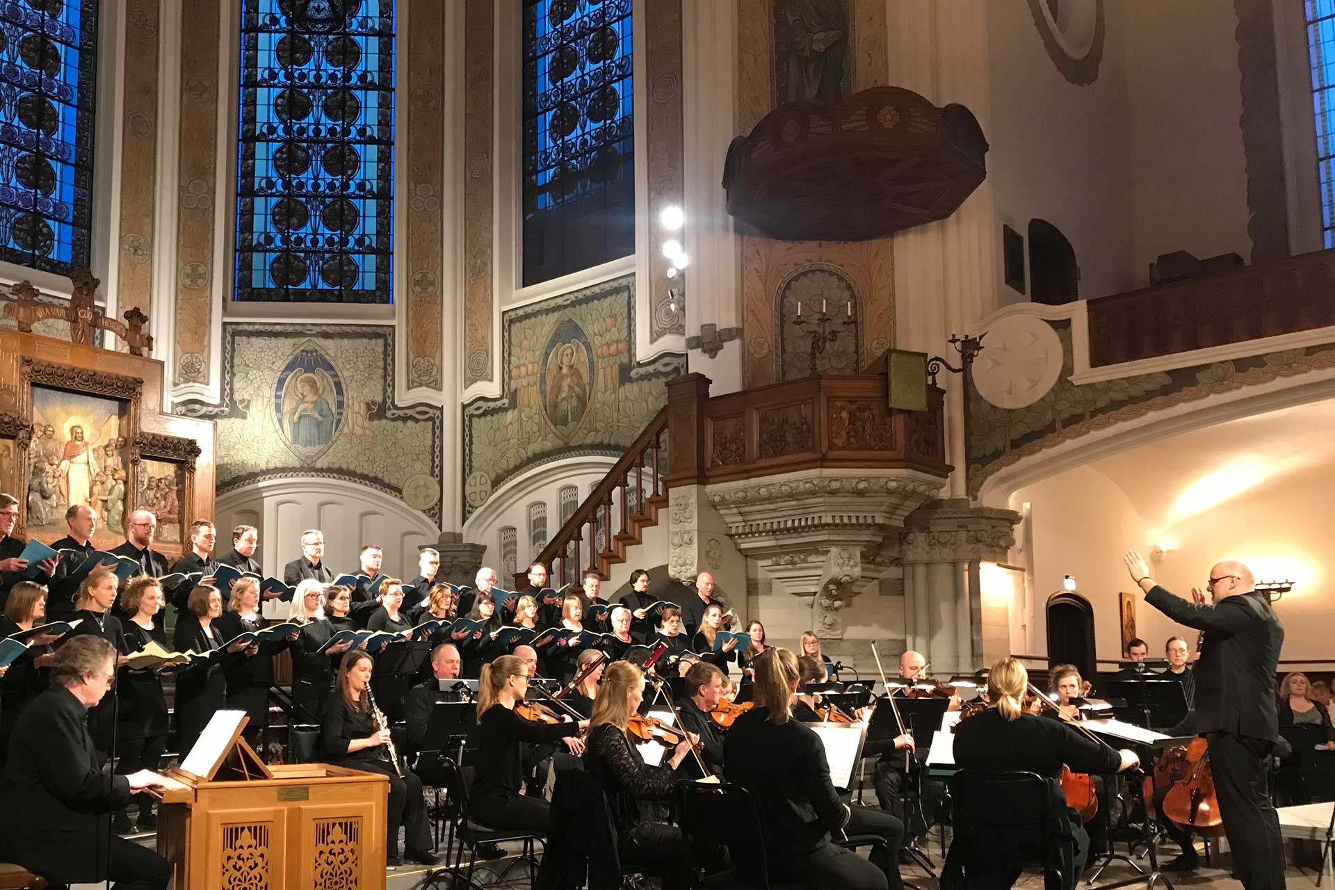 Sankt Johannes kammarkör tillsammans med musiker och dirigent sjunger i koret i S:t Johannes kyrka