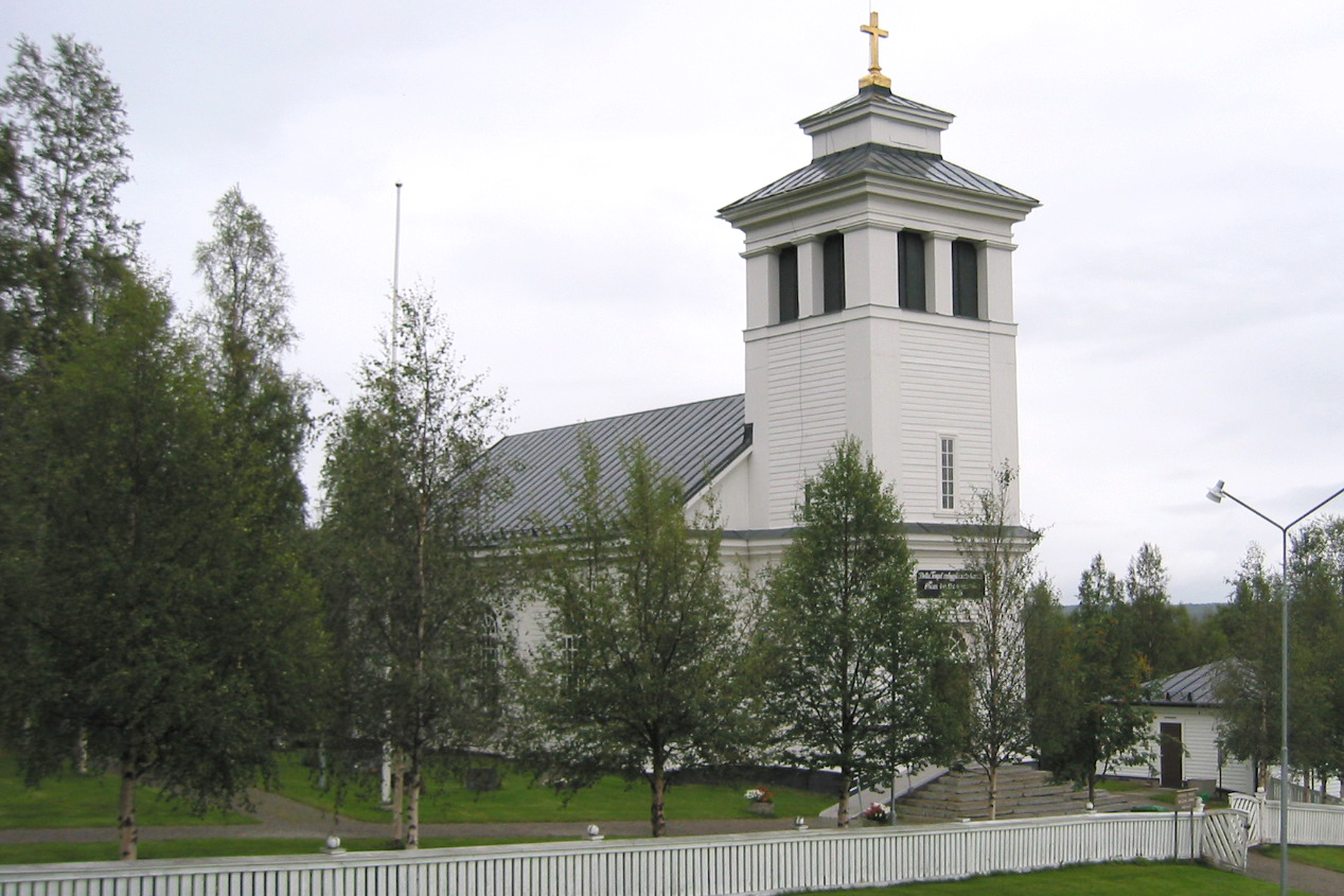 Tännäs kyrka med björkar och staket i förgrunden.