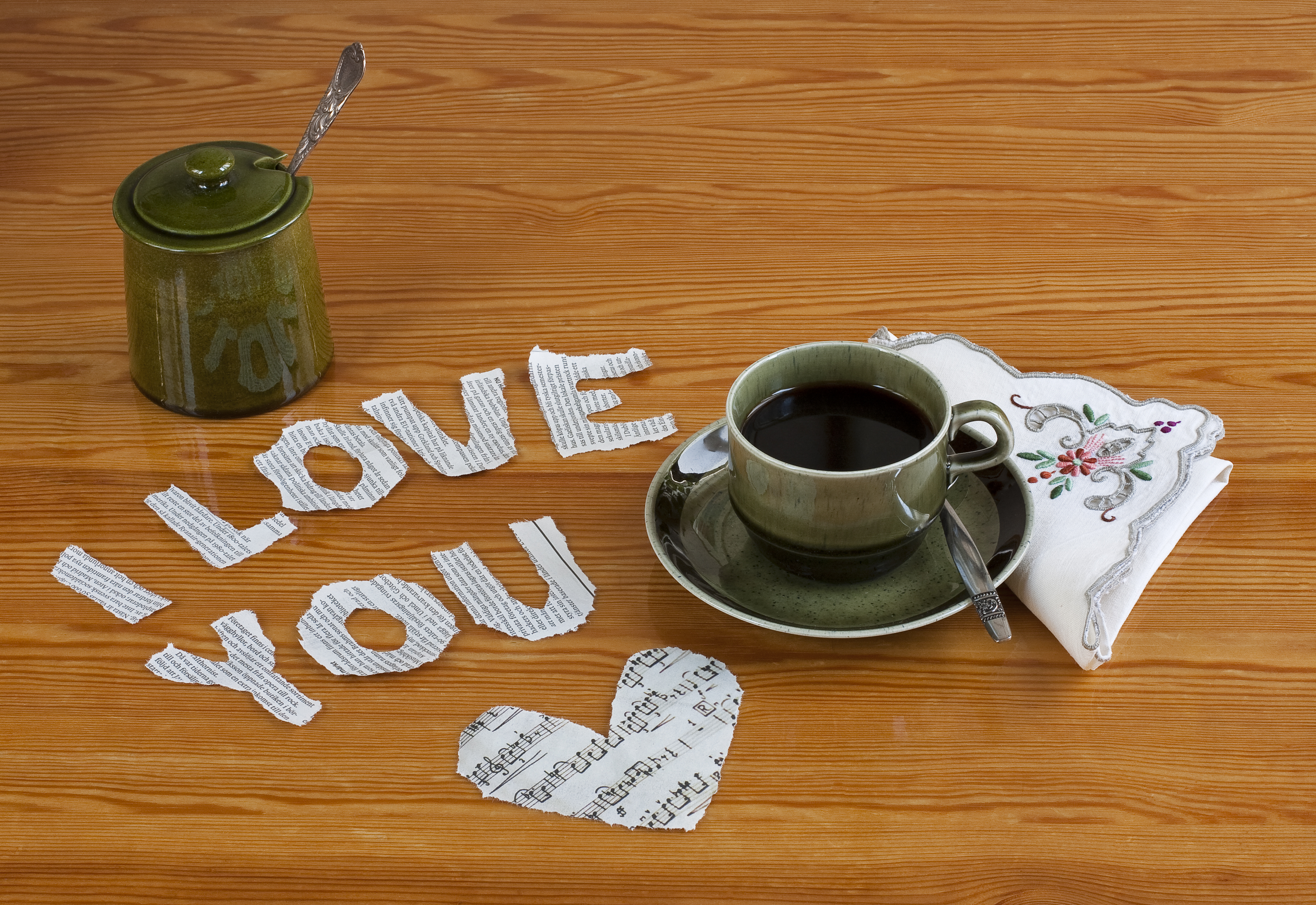 På ett bord ligger urklippta pappersbokstäver som bildar texten I love you. Bredvid står en kaffekopp.