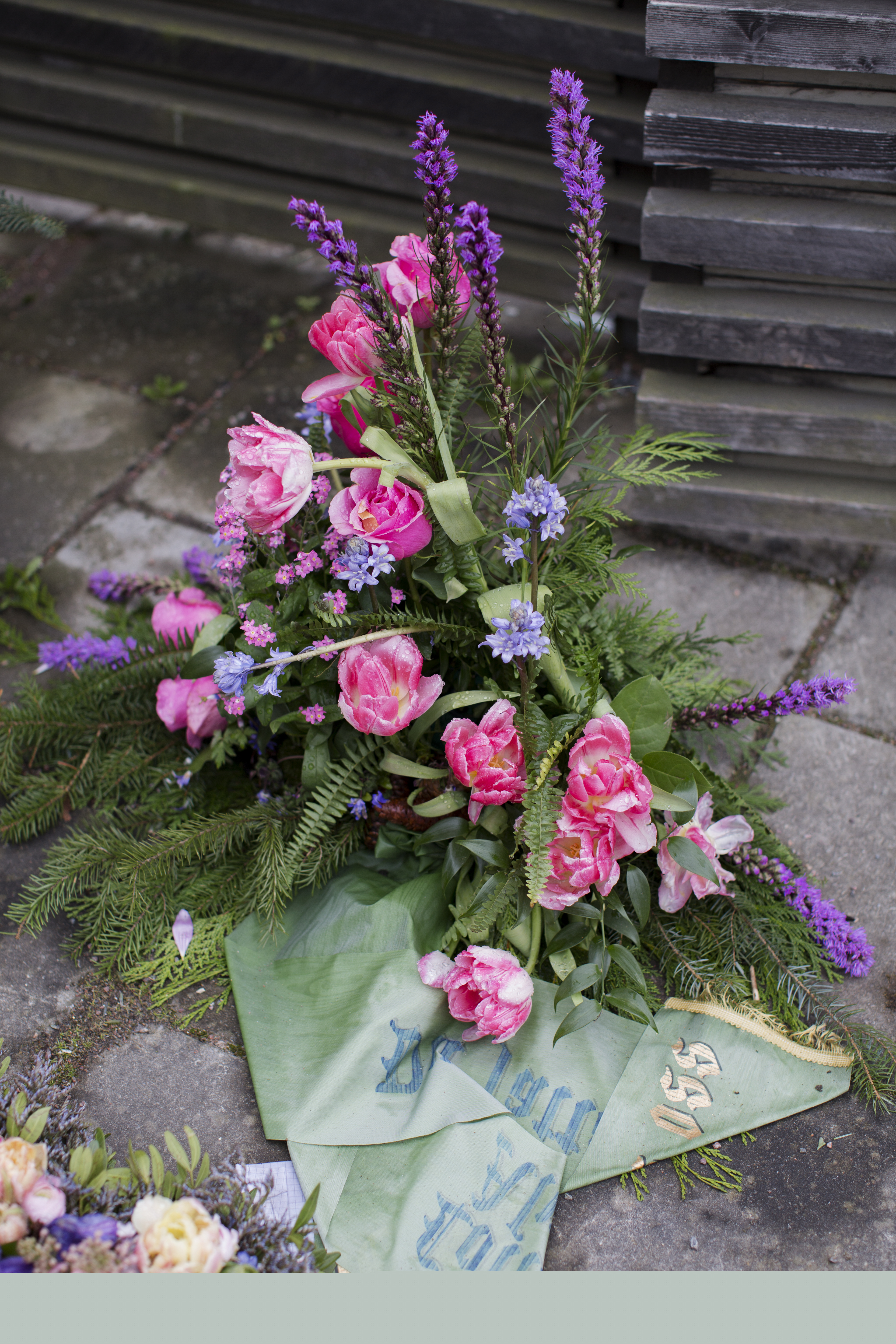 En stor begravningsbukett ligger utomhus på marken.