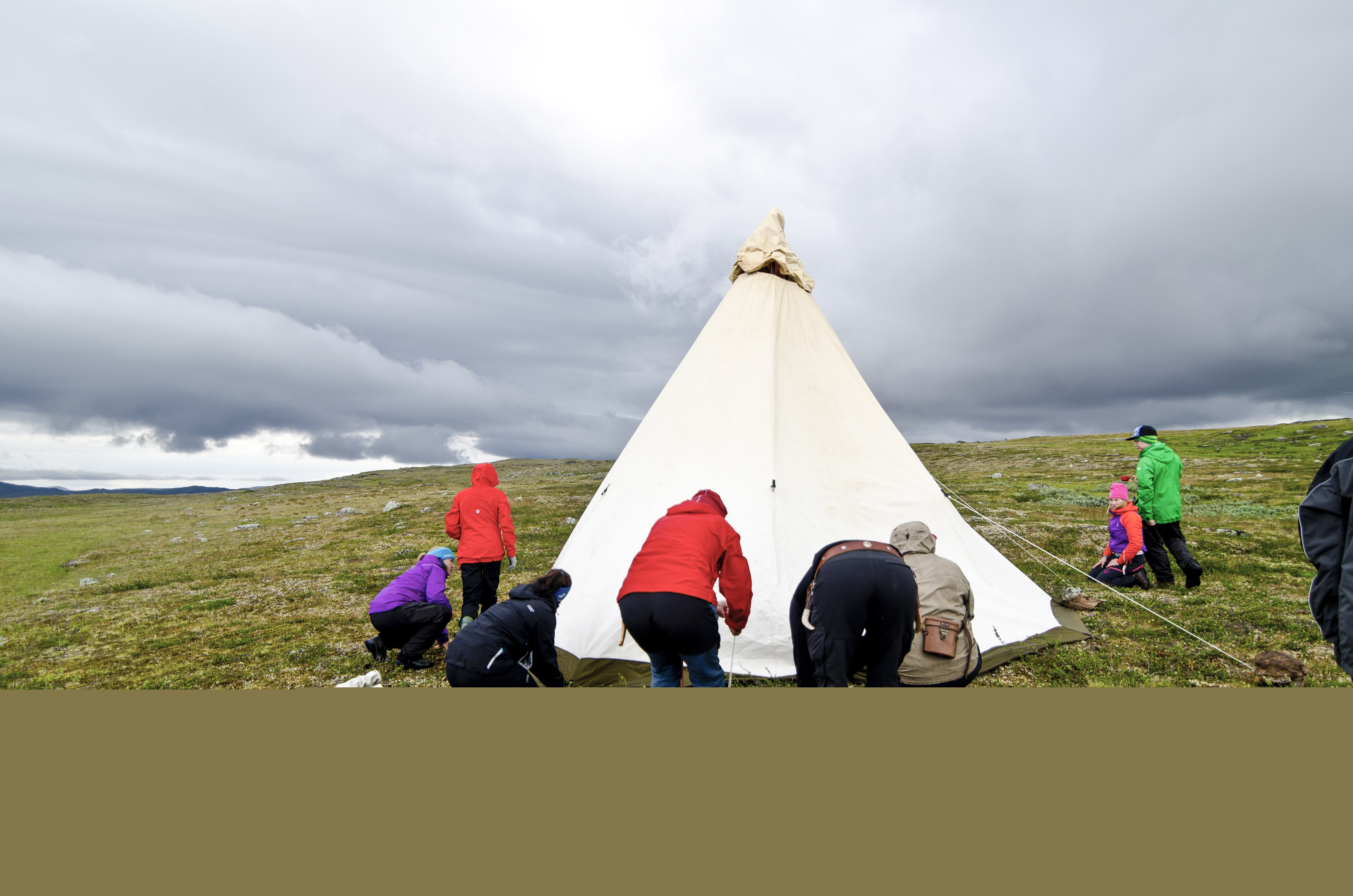 En grupp människor sätter upp ett tält på fjället.